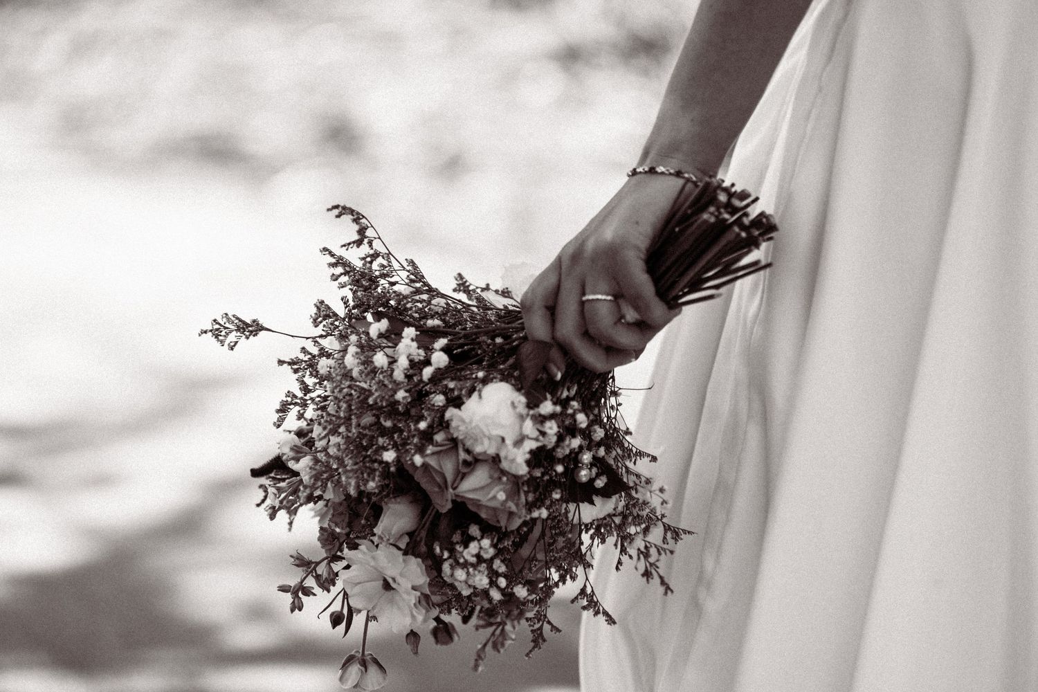 Black and white photo of bride holding a wildflower and greenery wedding bouquet.