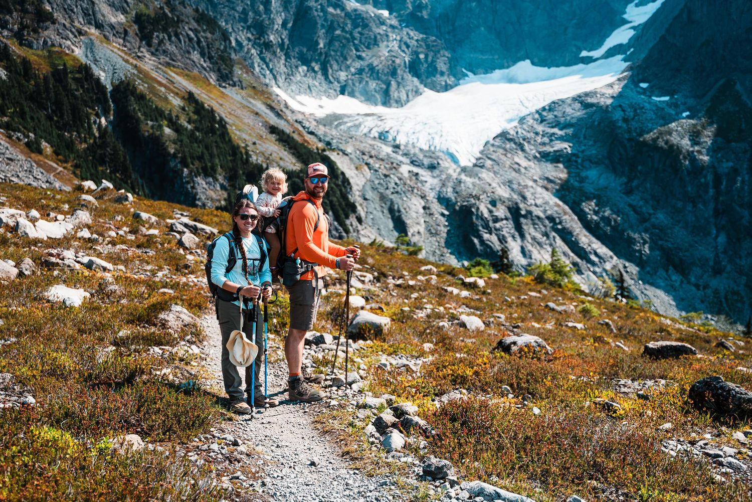 Hikers exploring alpine terrain with snow-capped mountains in background.