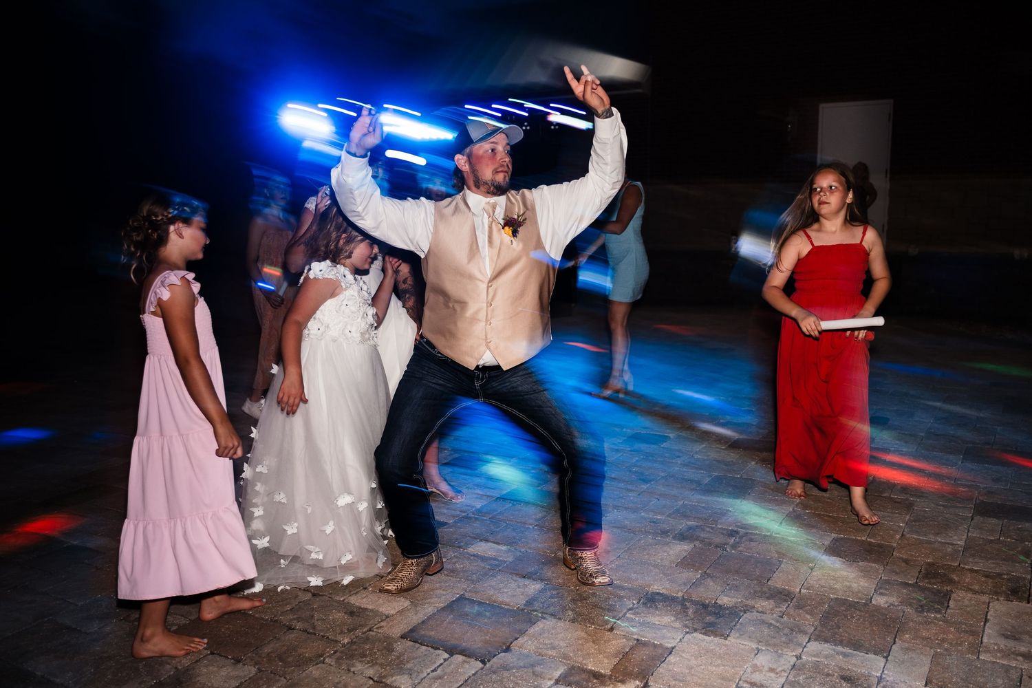 People dancing on a dark dance floor illuminated by blue lighting at an evening celebration.