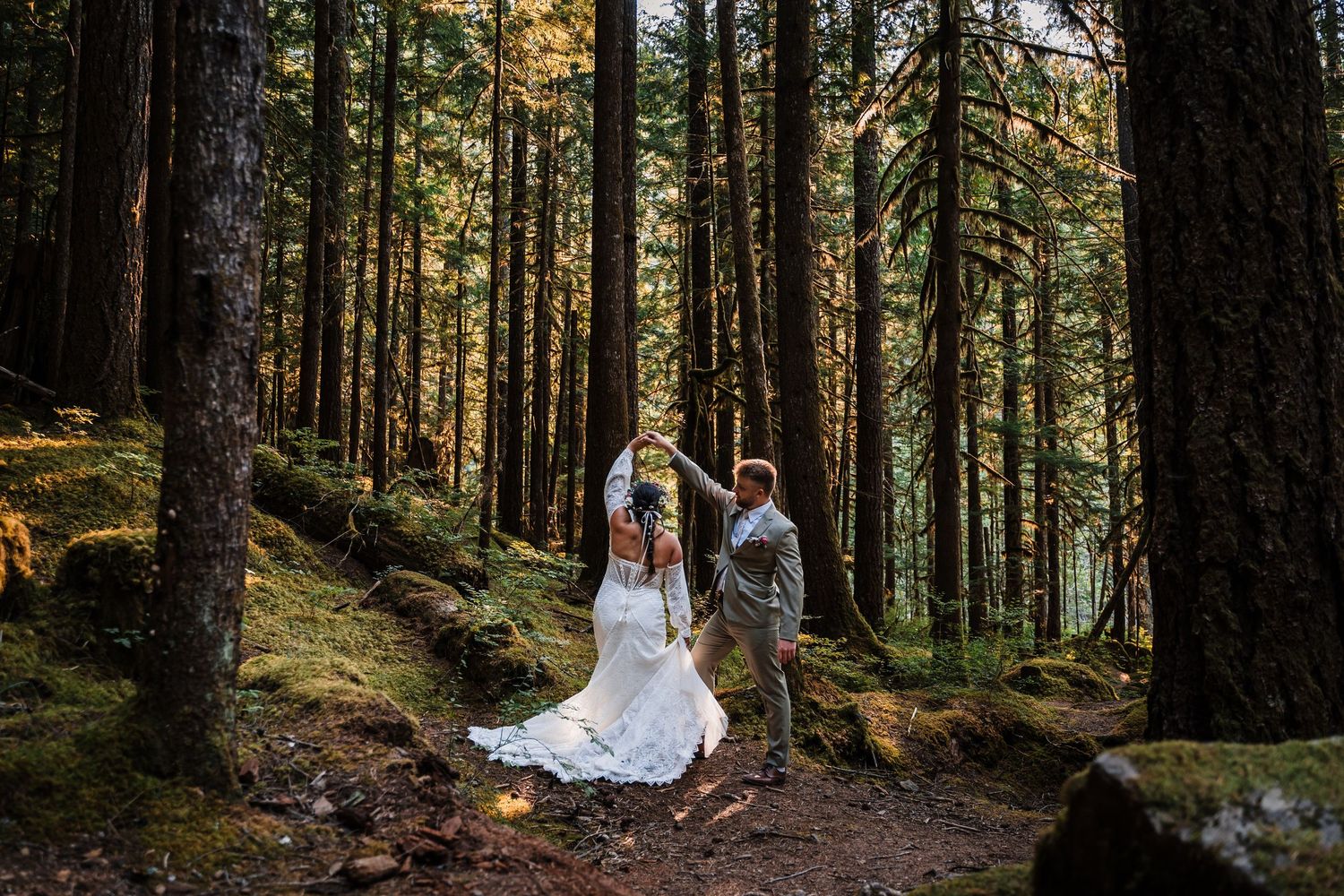 A romantic forest wedding photoshoot with sunlight filtering through tall evergreen trees in a Pacific Northwest setting.