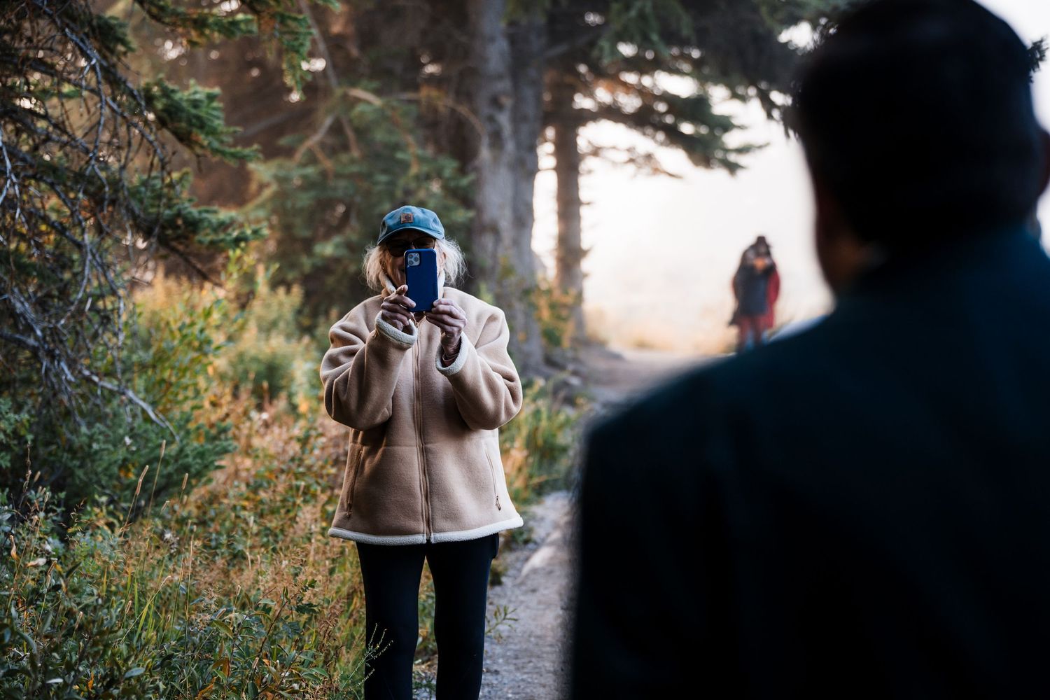 Silhouettes of wedding photographers capturing moments in a forest setting.