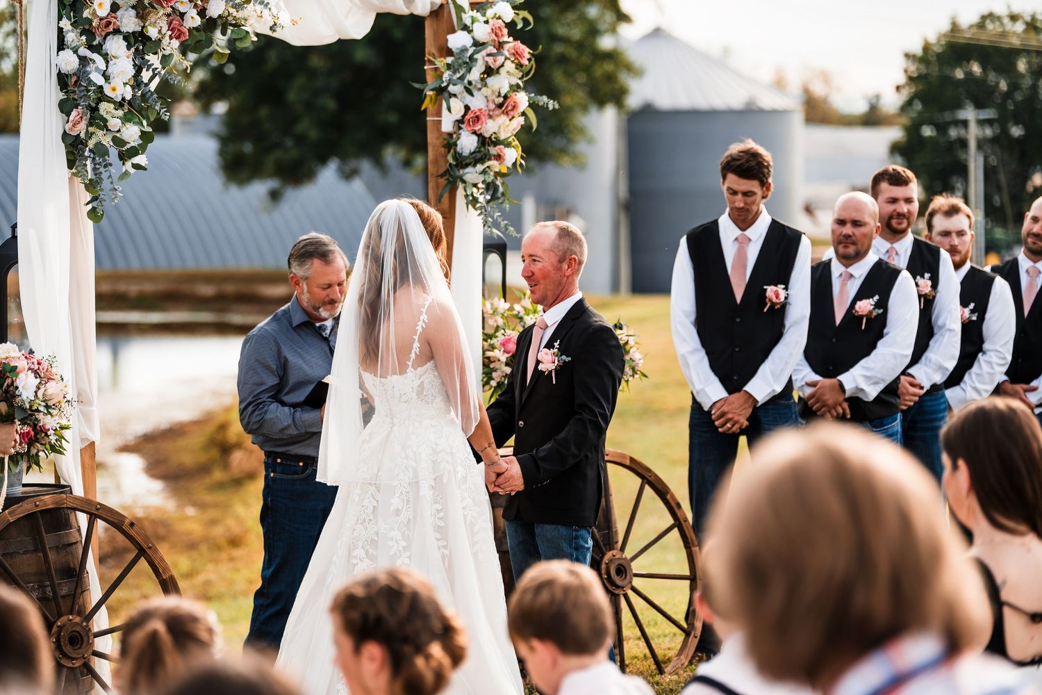 Wide shot of an outdoor wedding ceremony setup with floral arrangements and white chairs.