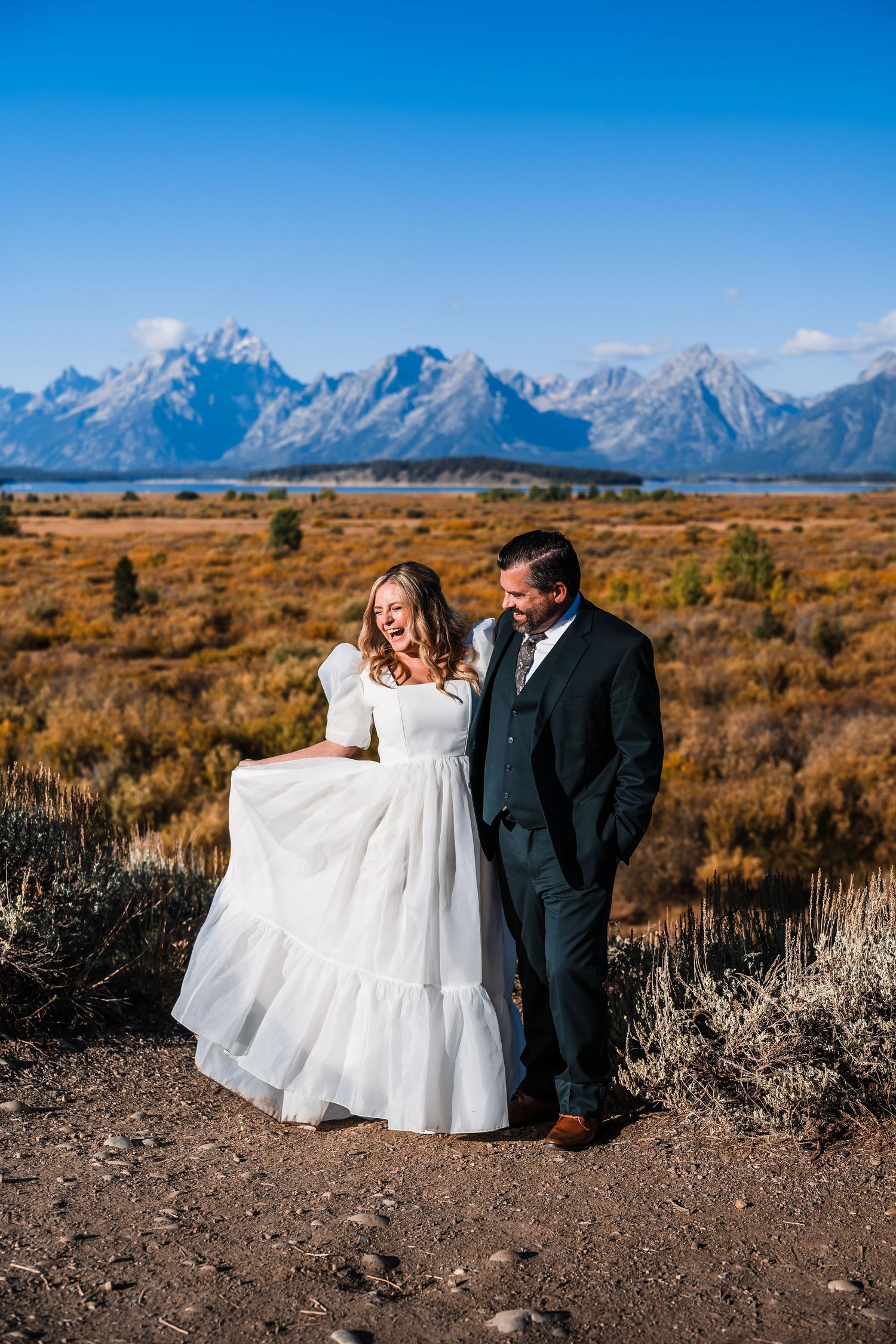 Wedding couple poses in front of majestic Grand Teton mountains on their special day.