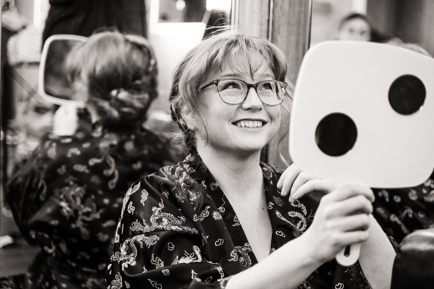 A person smiles while holding up large decorative dice during a celebration.