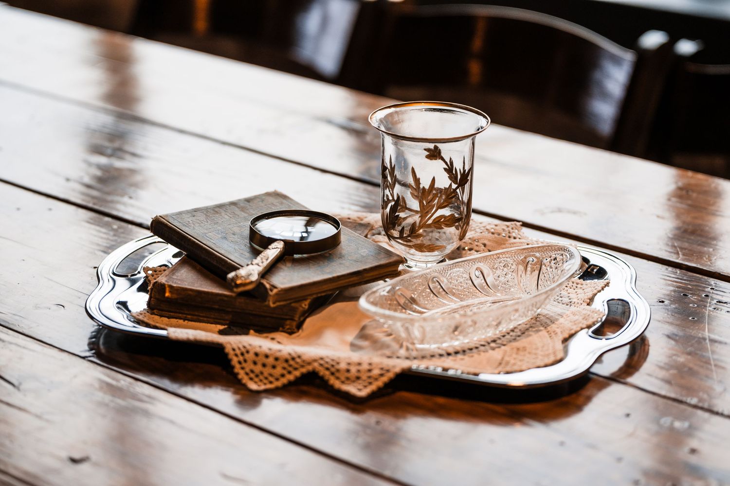 Wedding details including rings and cards arranged on rustic wooden table with glass.