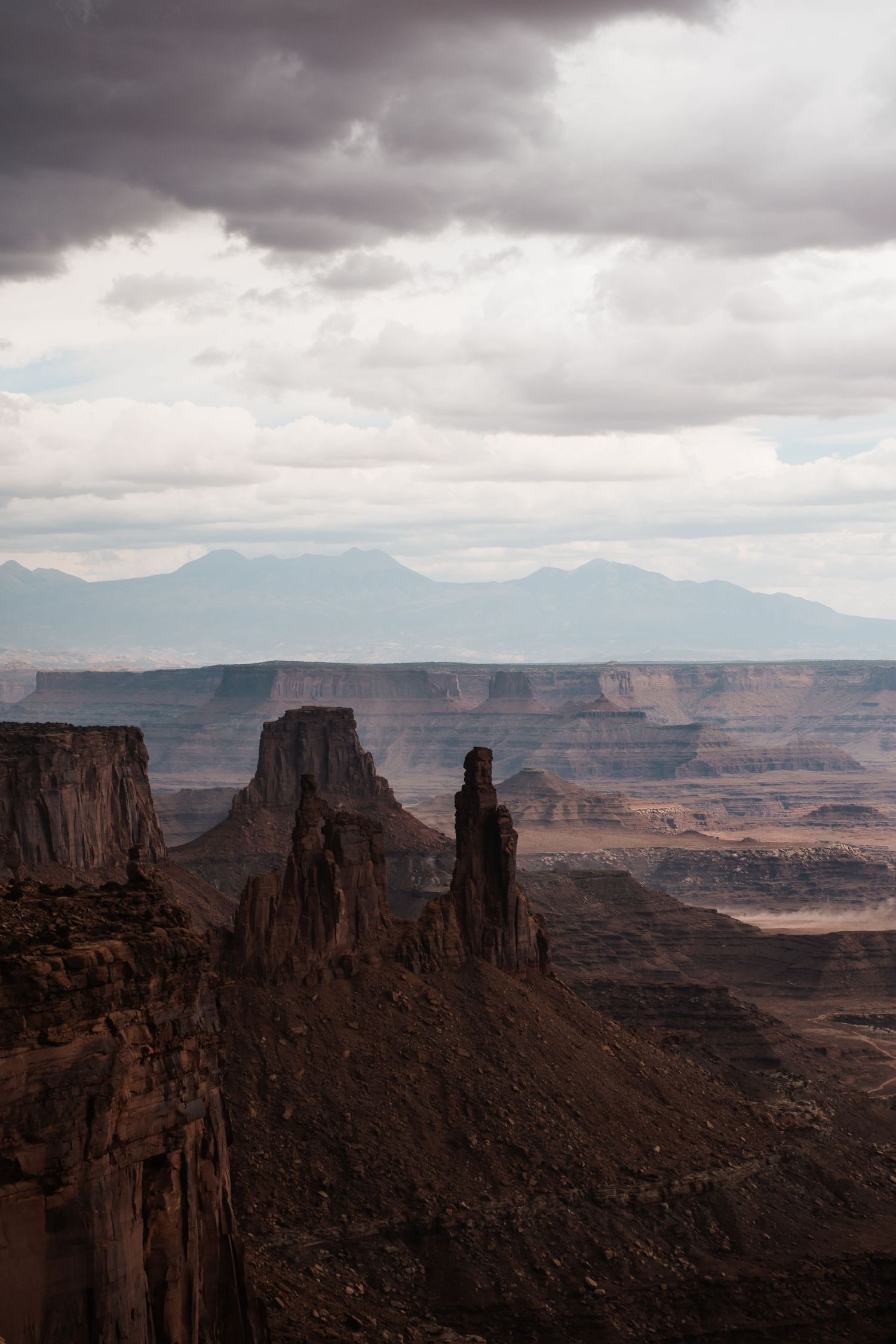 Dramatic rock formations and towering buttes stand against stormy skies at Canyonlands National Park in Utah.