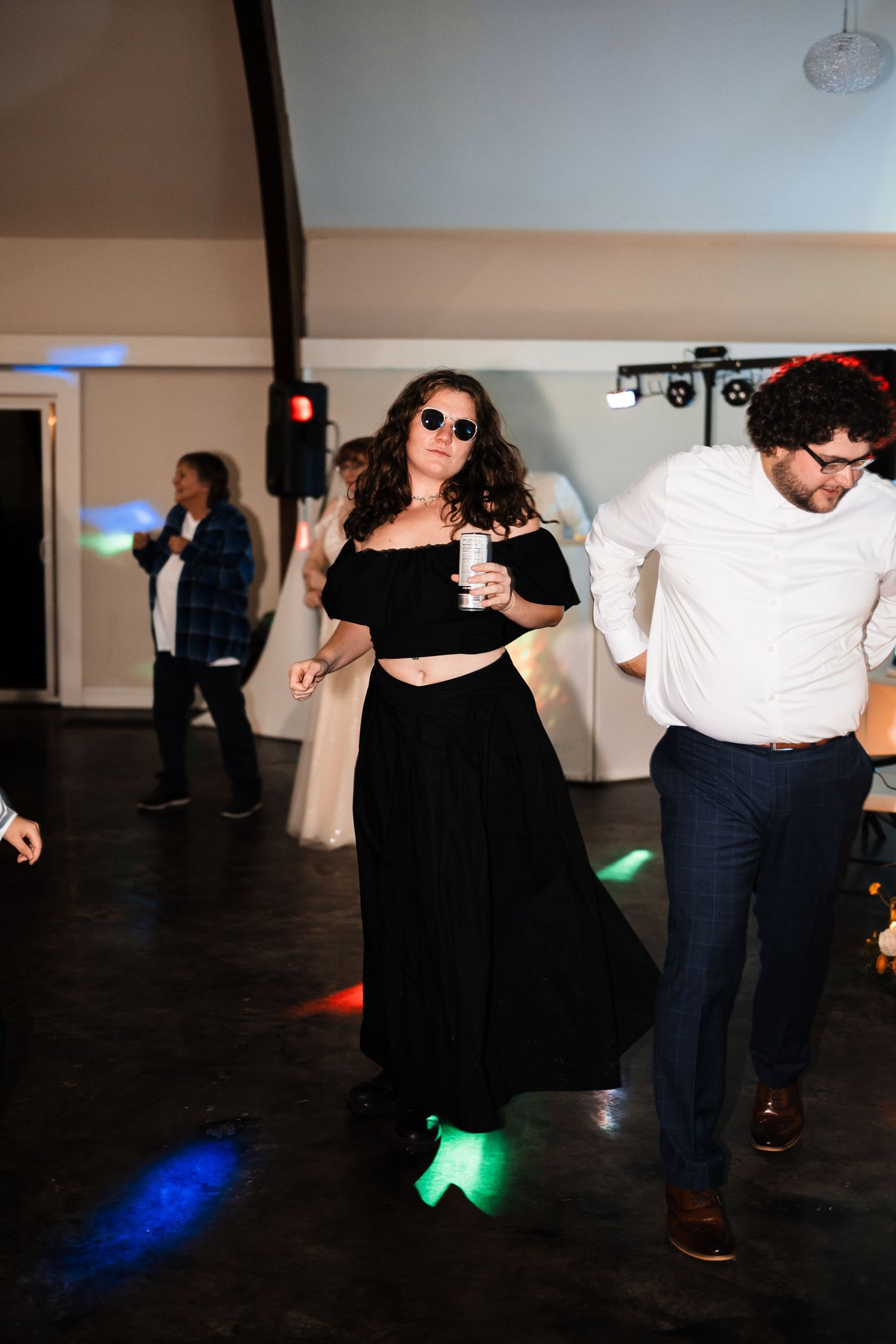 Dancing partygoers enjoy themselves on a dark dance floor with colorful lighting.
