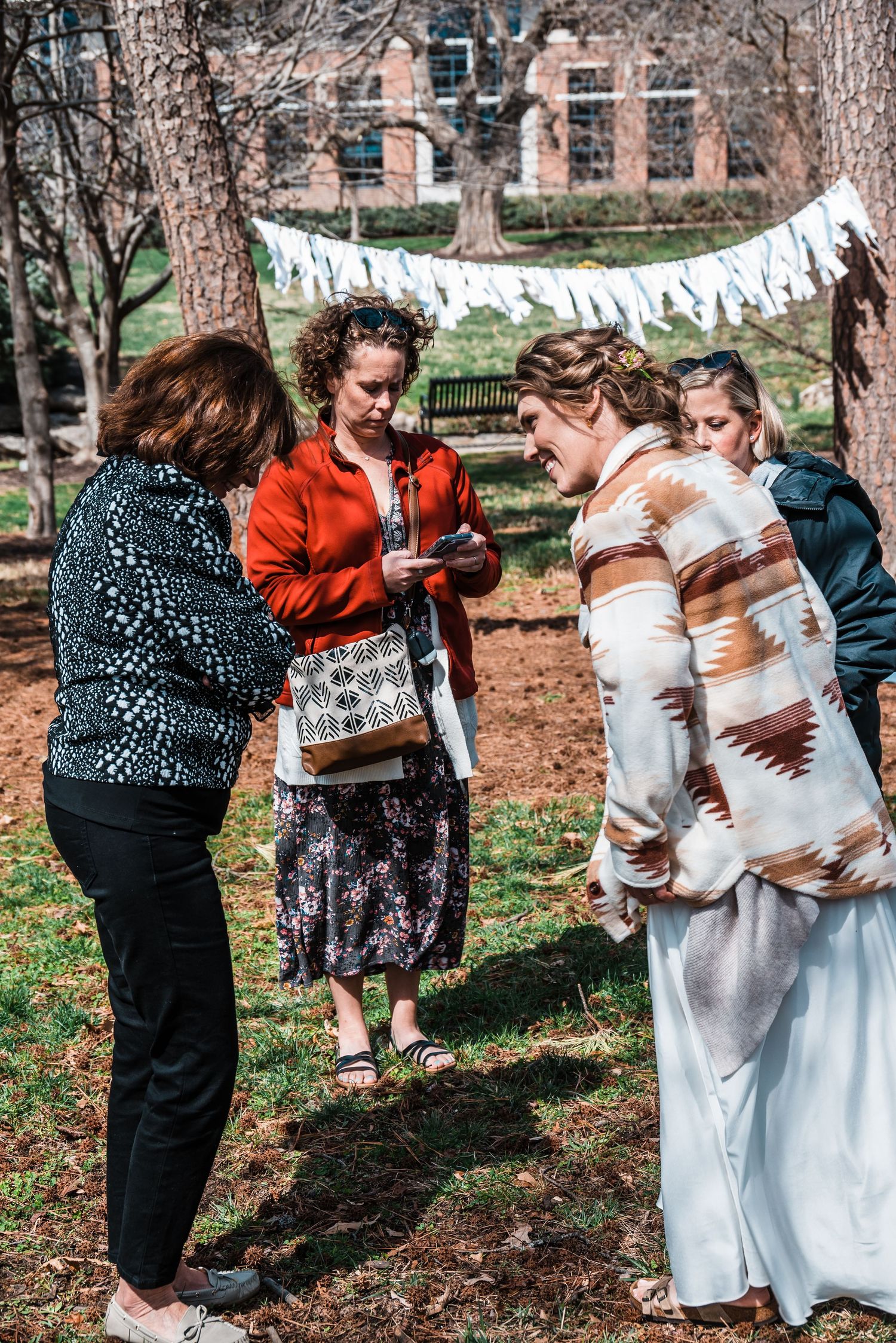 Wedding celebration in park with guests gathered under banner decorations.