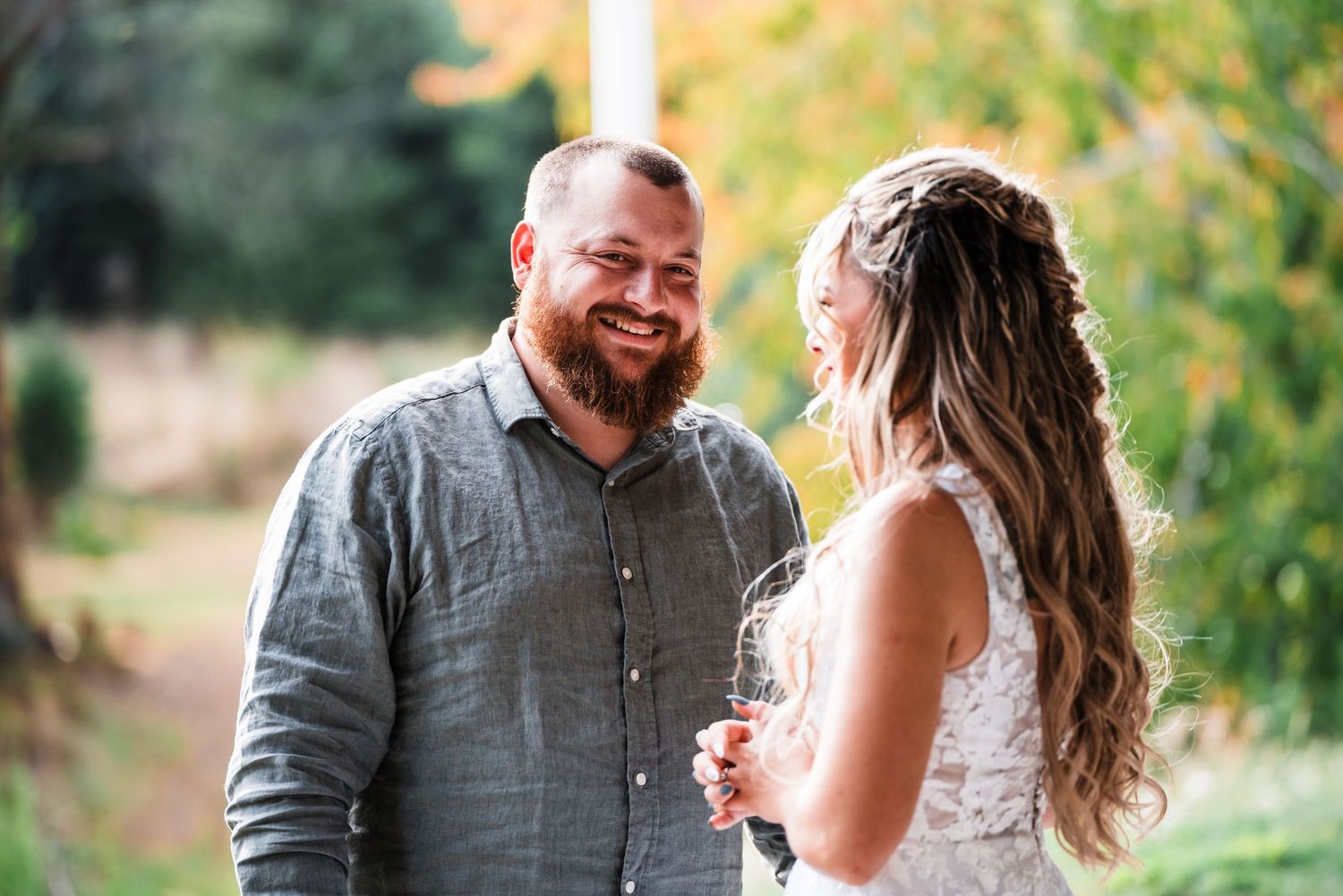 Candid outdoor wedding moment with natural lighting and greenery in background.