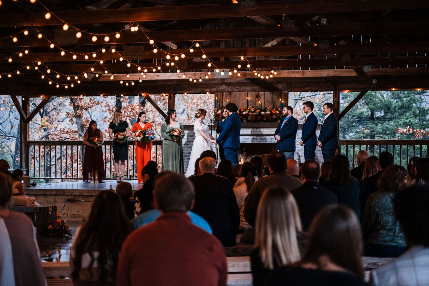 Wedding ceremony attendees watching celebration from seats in rustic venue.