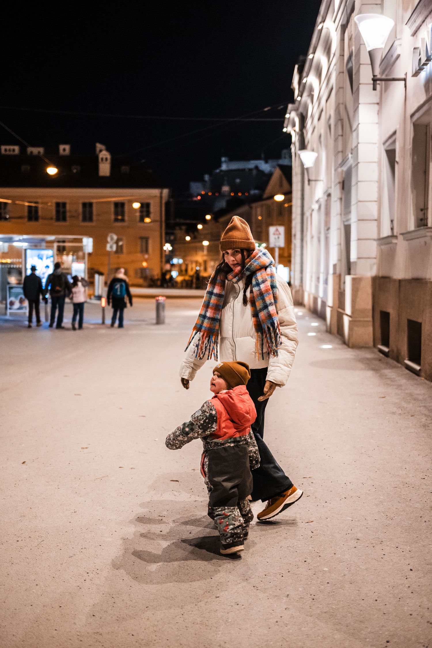 A sequence of photos shows someone learning to skateboard at night in an illuminated outdoor plaza.