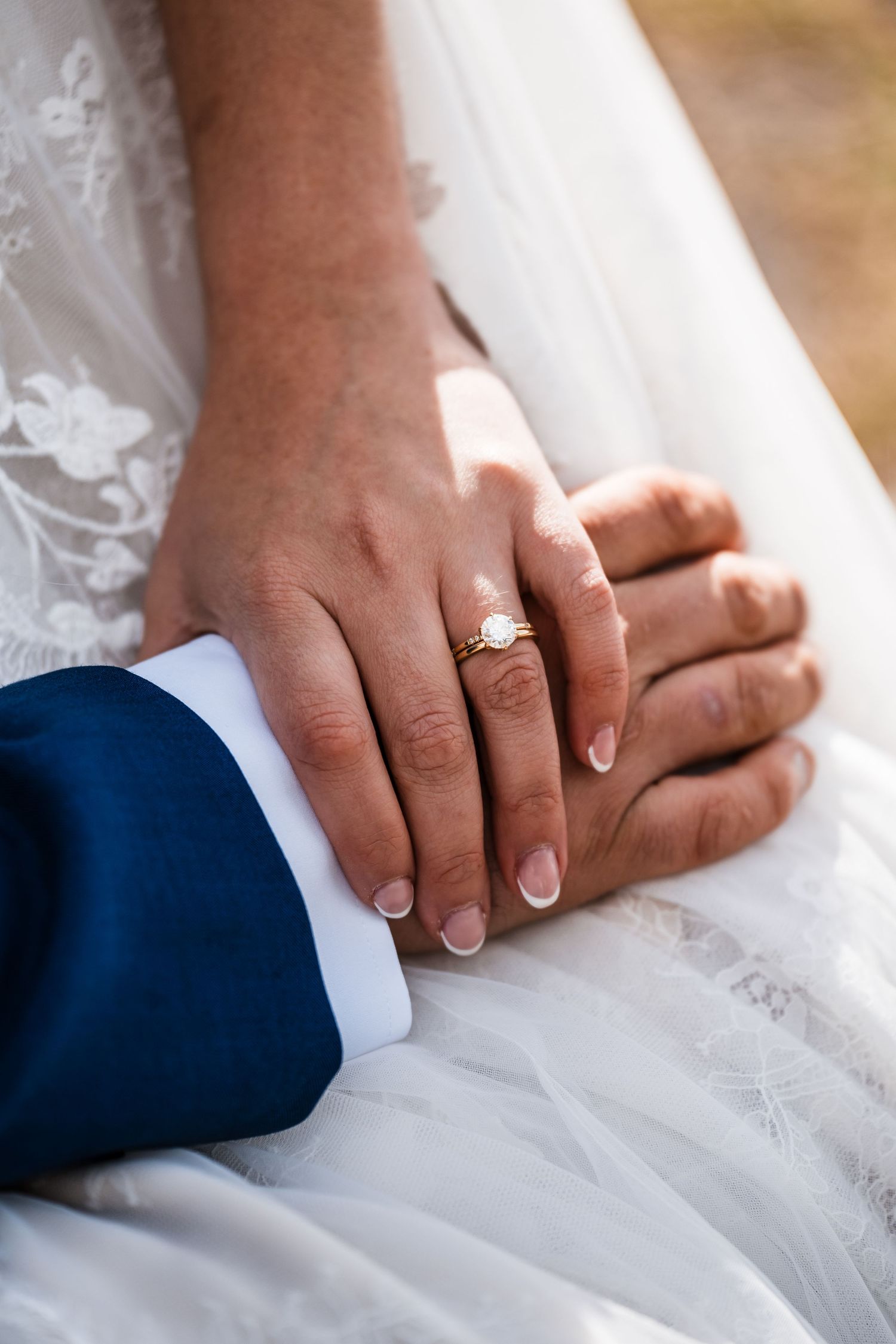 Close-up shots of hands with wedding rings against white lace dress fabric.