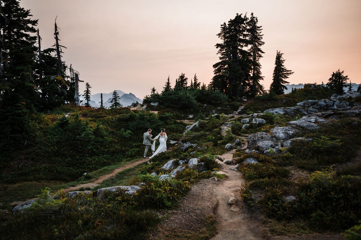 Winding mountain trail leading to sunset viewpoint with evergreen trees.