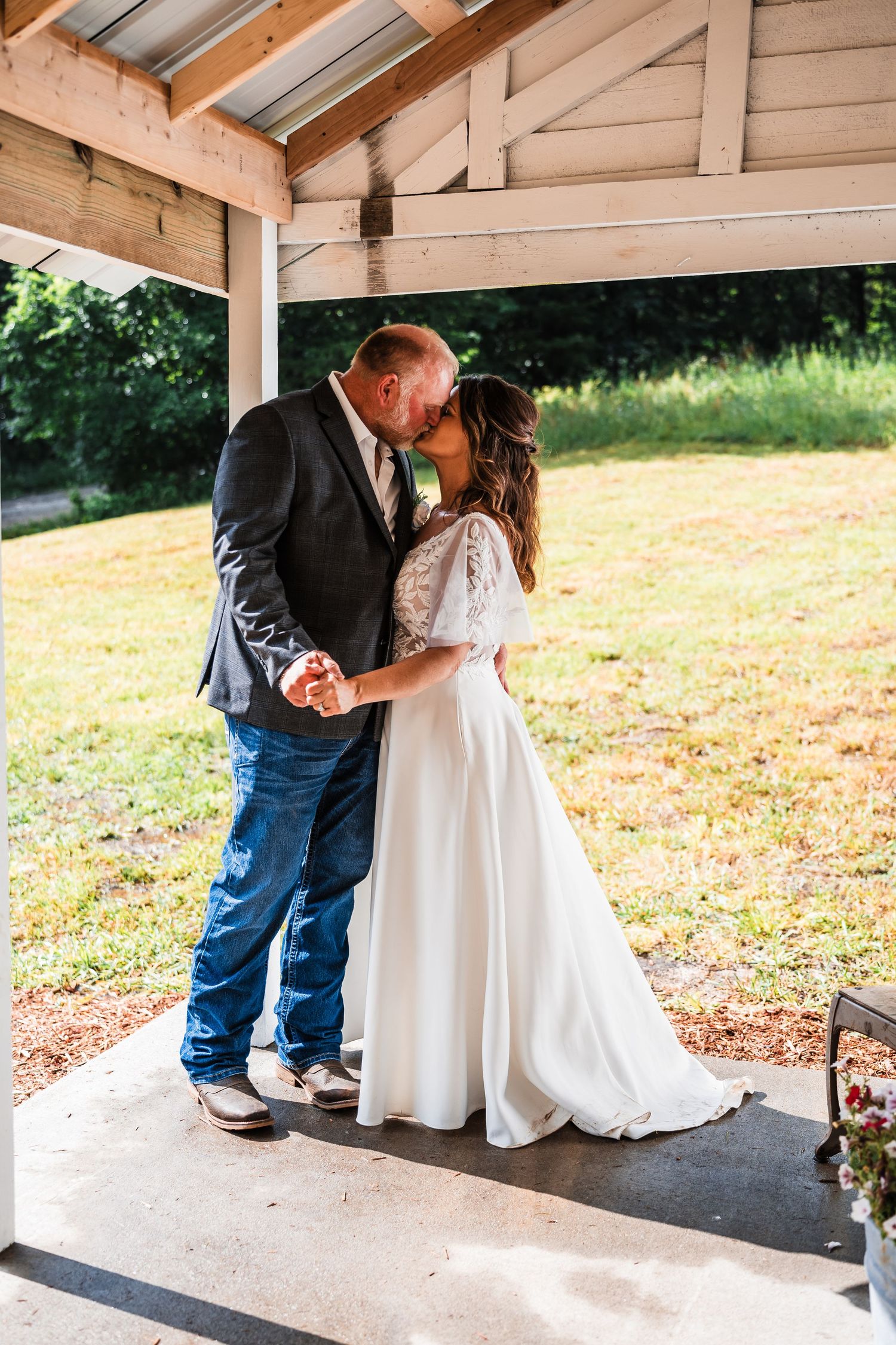 Wedding couple sharing intimate moments under a covered outdoor pavilion.
