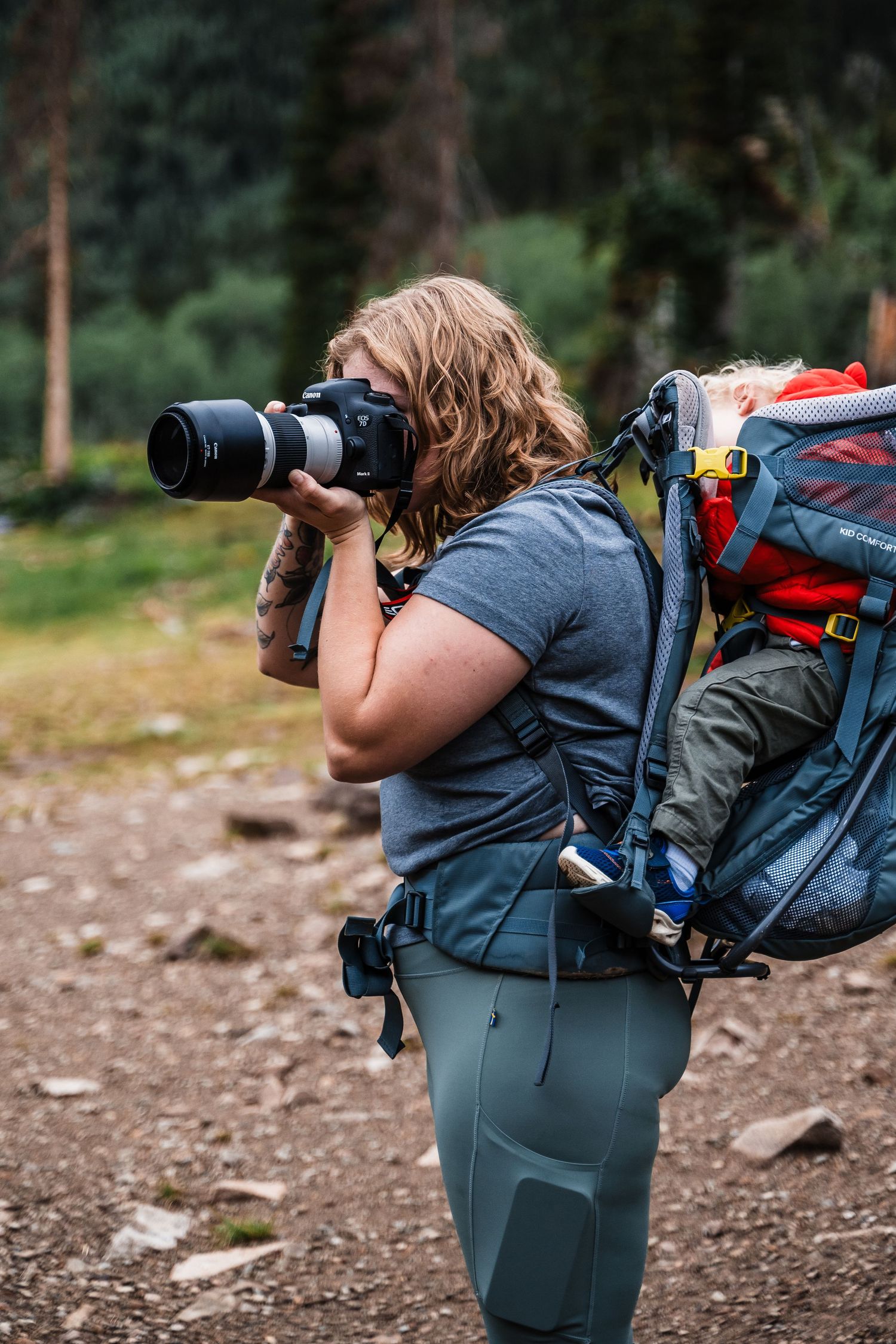 Adventure photographer with backpack takes photos on mountain trail.