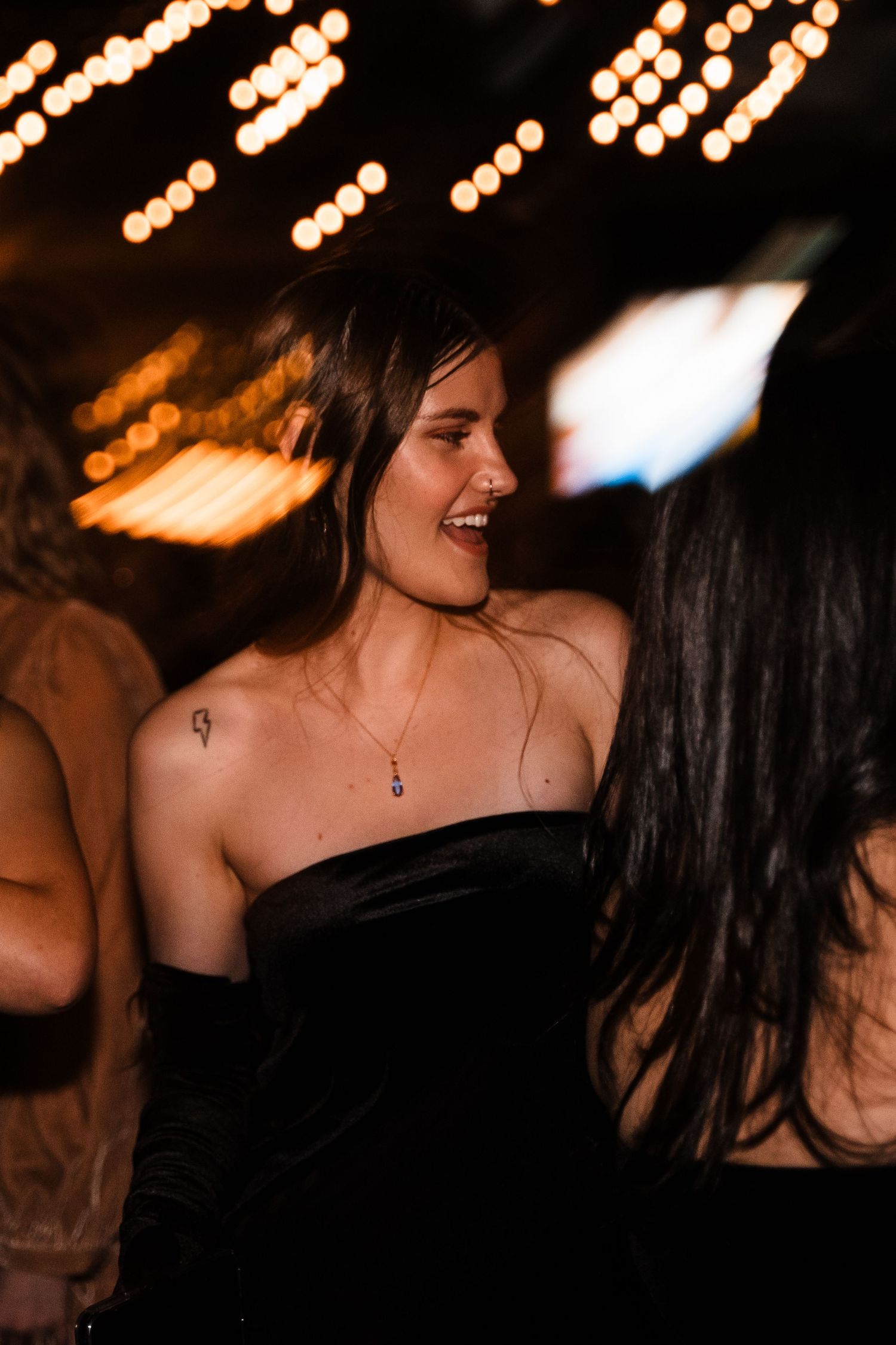 A joyful celebration moment captured under warm glowing lights at a party venue.