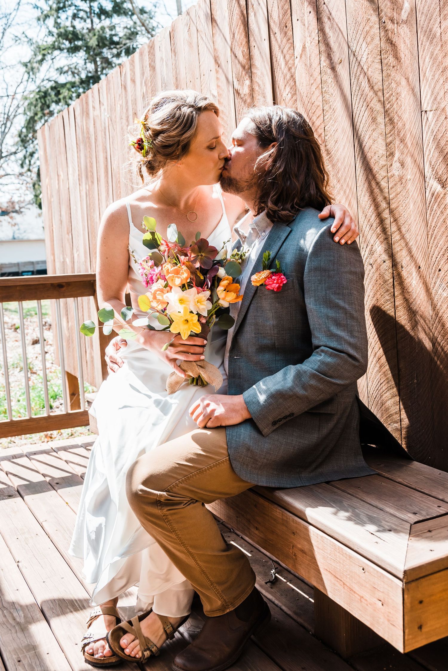 Intimate wedding moment on wooden deck with couple sharing tender embrace.