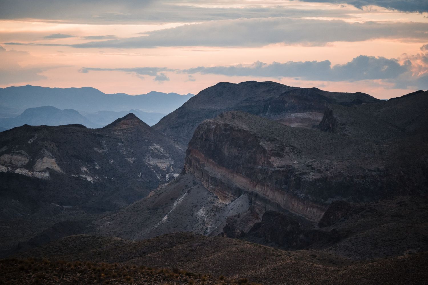 Majestic mountain peaks and valleys captured during dusk with dramatic cloud formations.