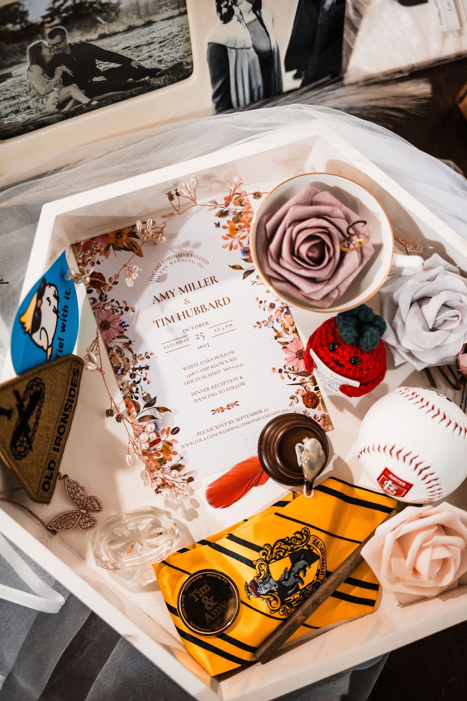 Wedding invitation details with baseball theme elements and rose decorations arranged in a flat lay.