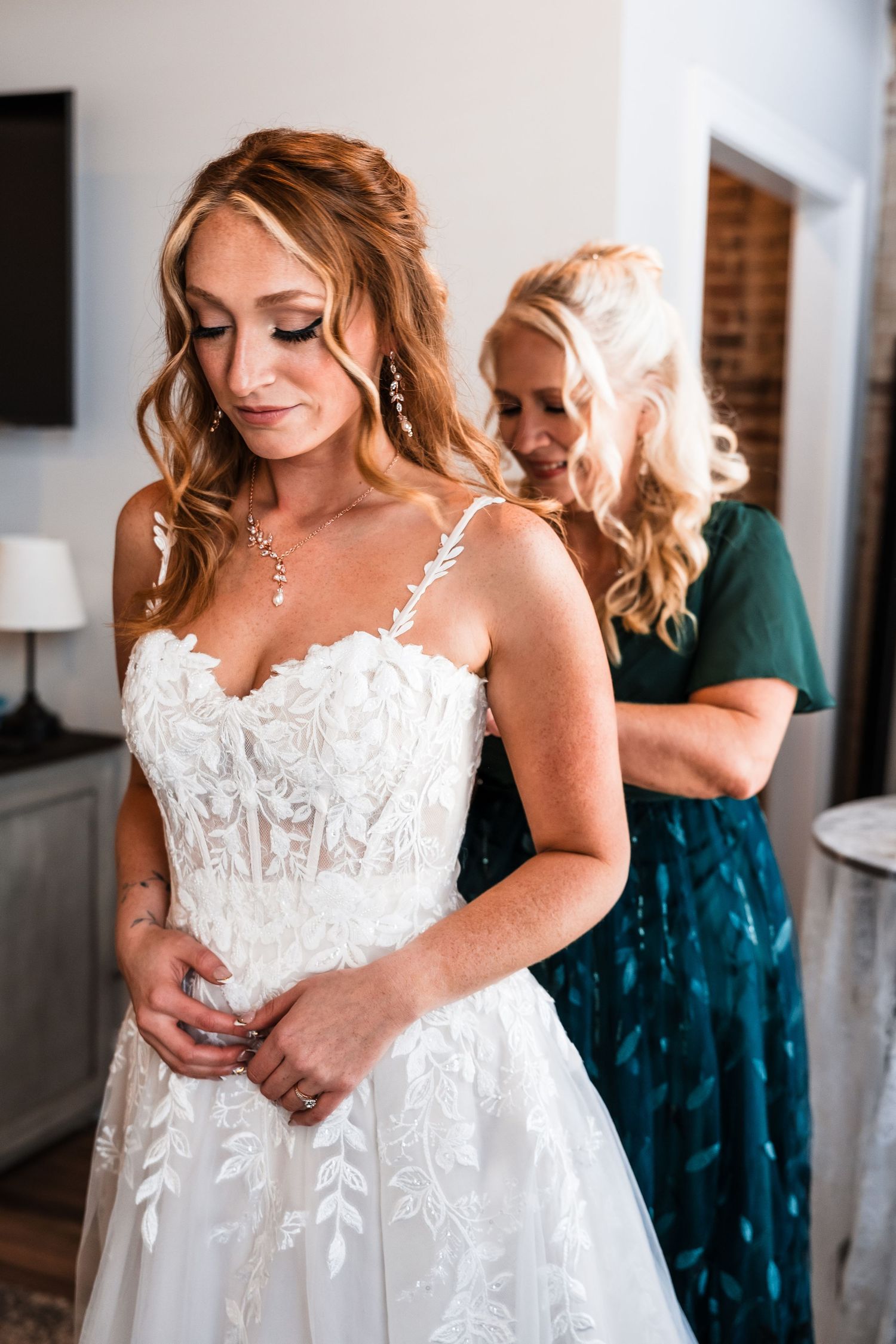 Close up details of a beautiful white lace wedding dress with delicate floral appliques and spaghetti straps.