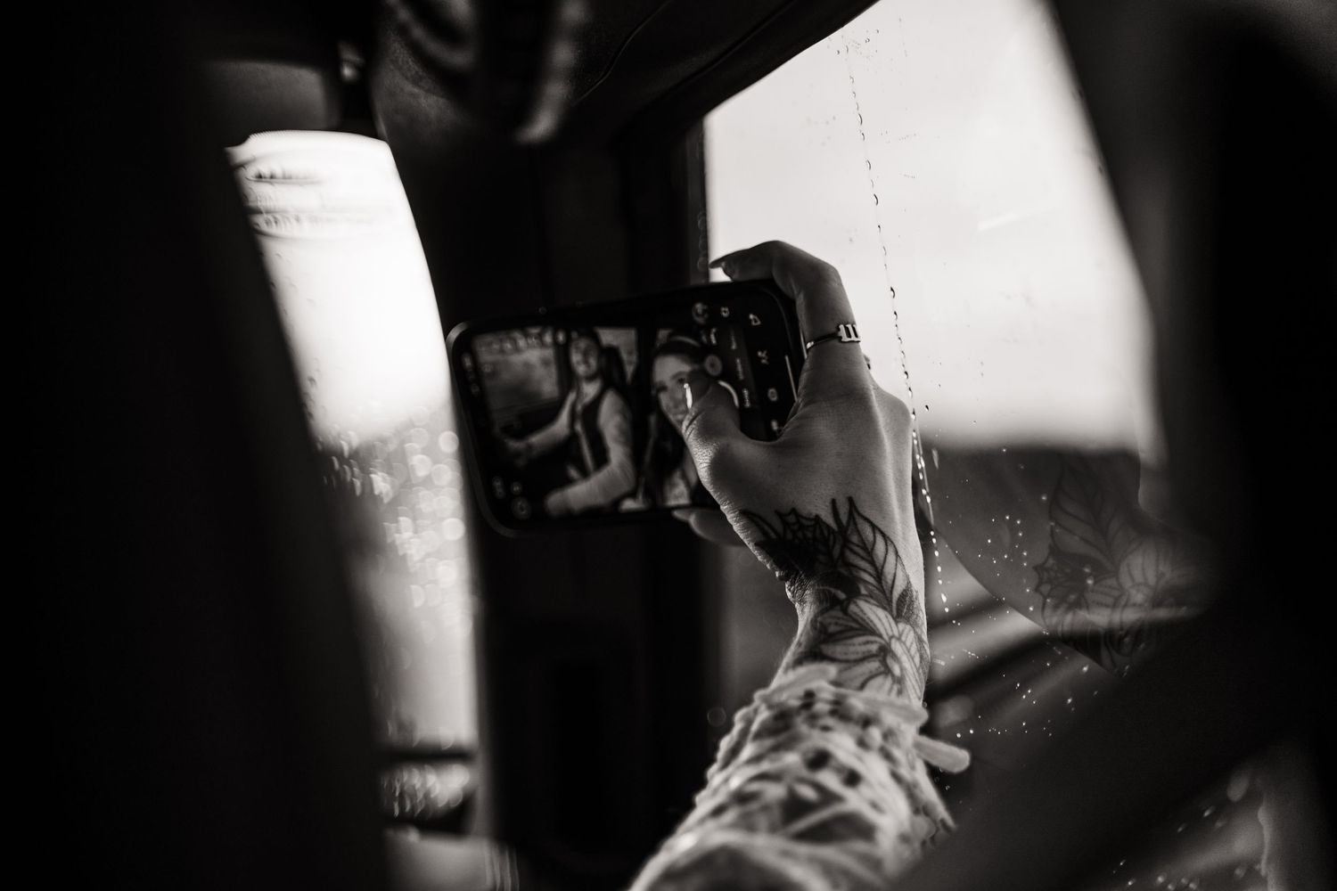 Black and white image of a photographer capturing a shot through a camera lens.