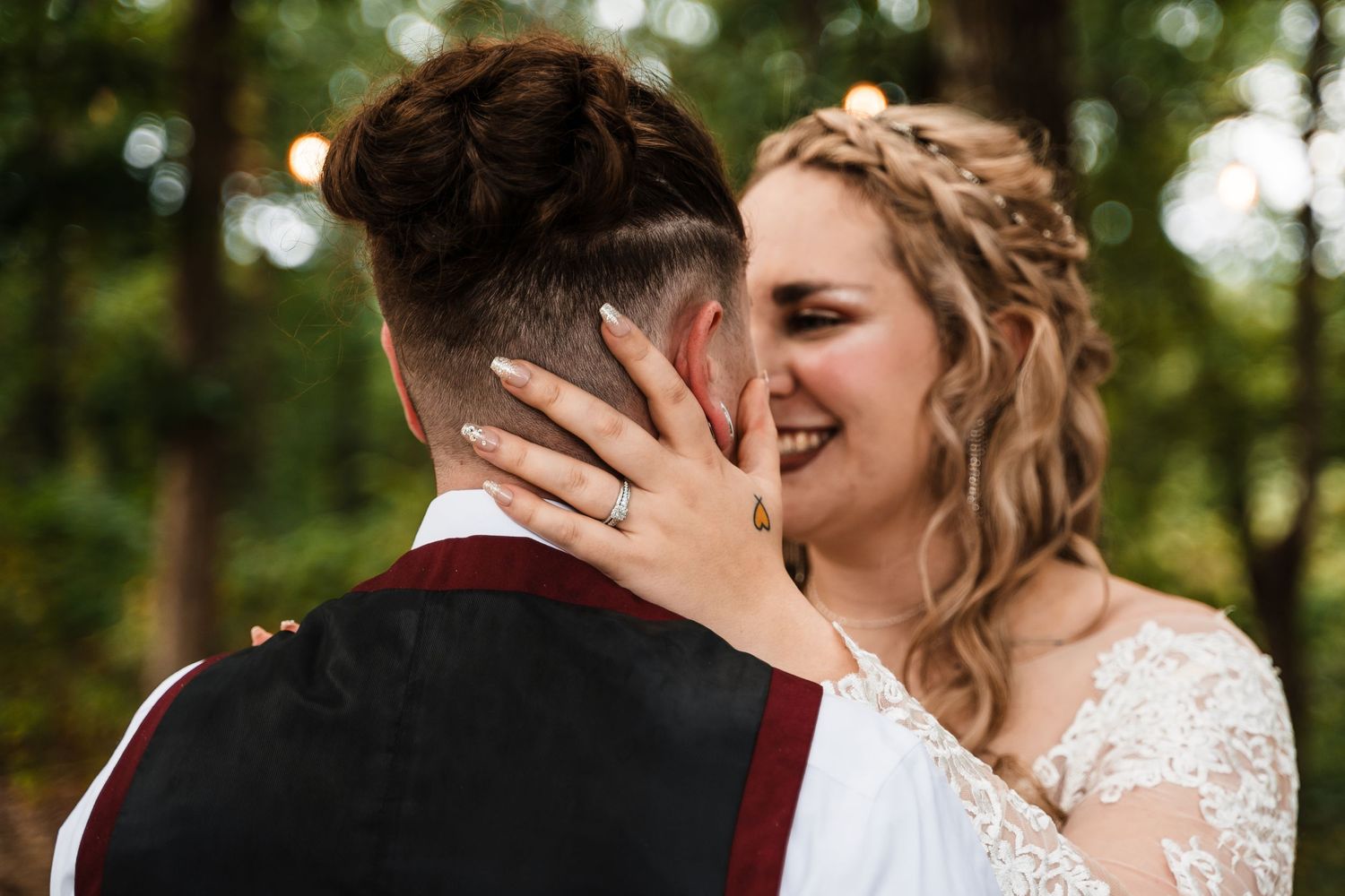 An intimate moment between a couple in wedding attire outdoors.