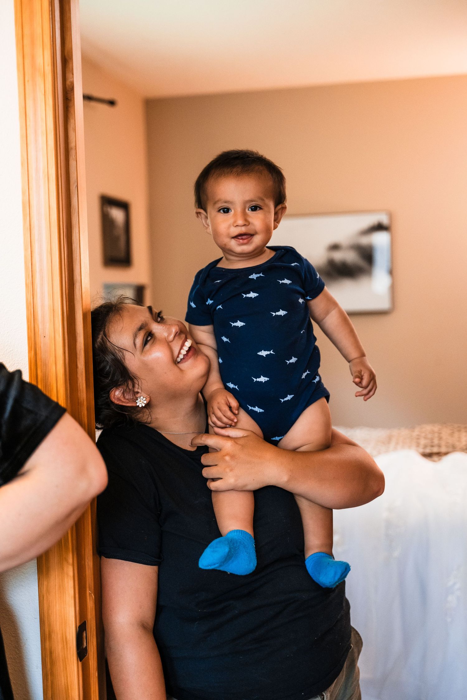 A parent and happy child wearing blue socks share a joyful moment together in a bedroom.