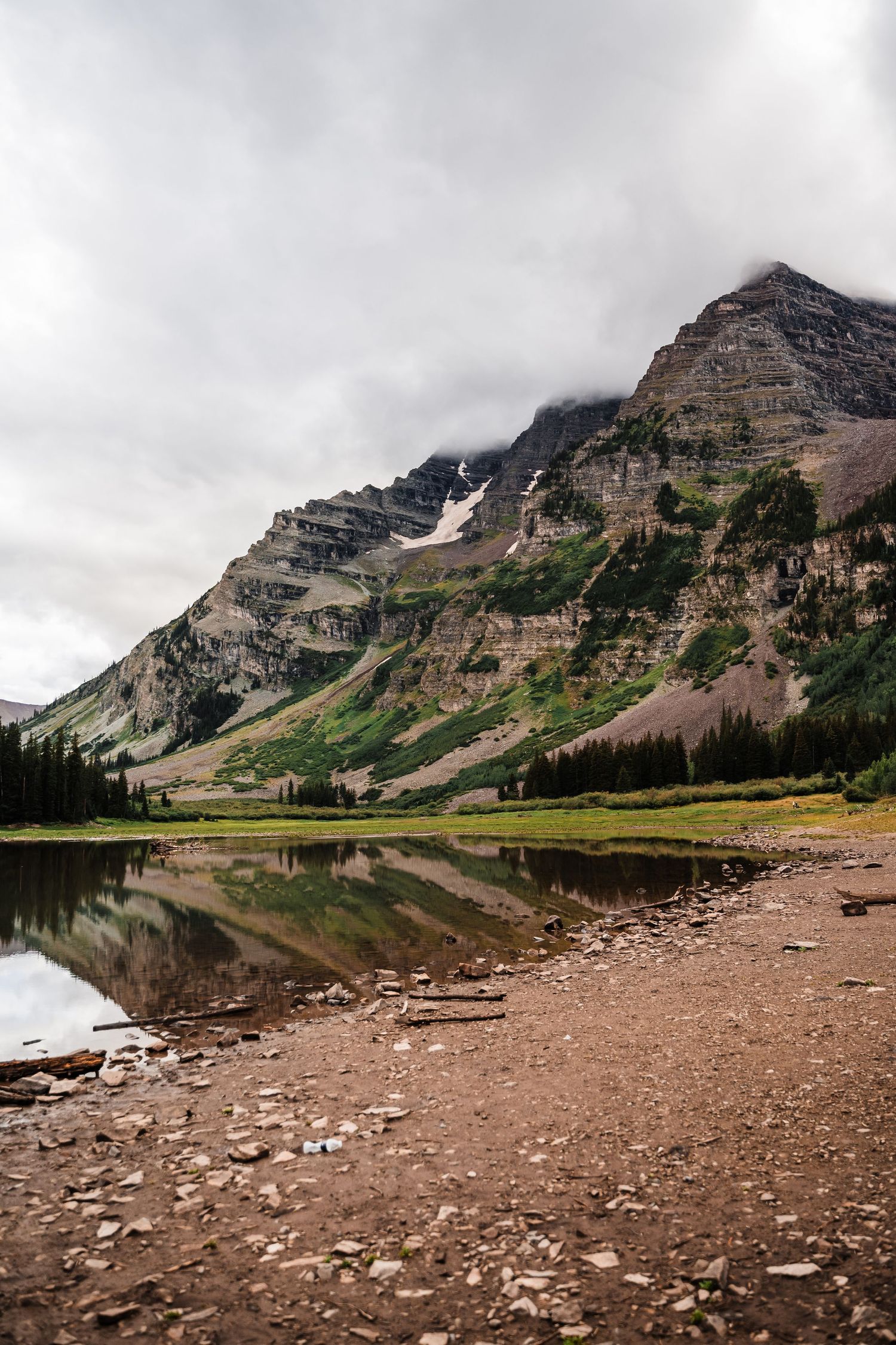 Dramatic mountain reflections in alpine lake with rocky shoreline.