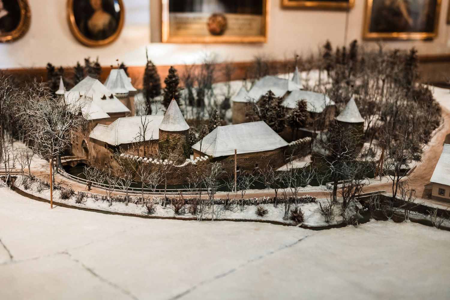 Miniature model display of snow-covered winter village with tiny houses and trees arranged in a circular formation.