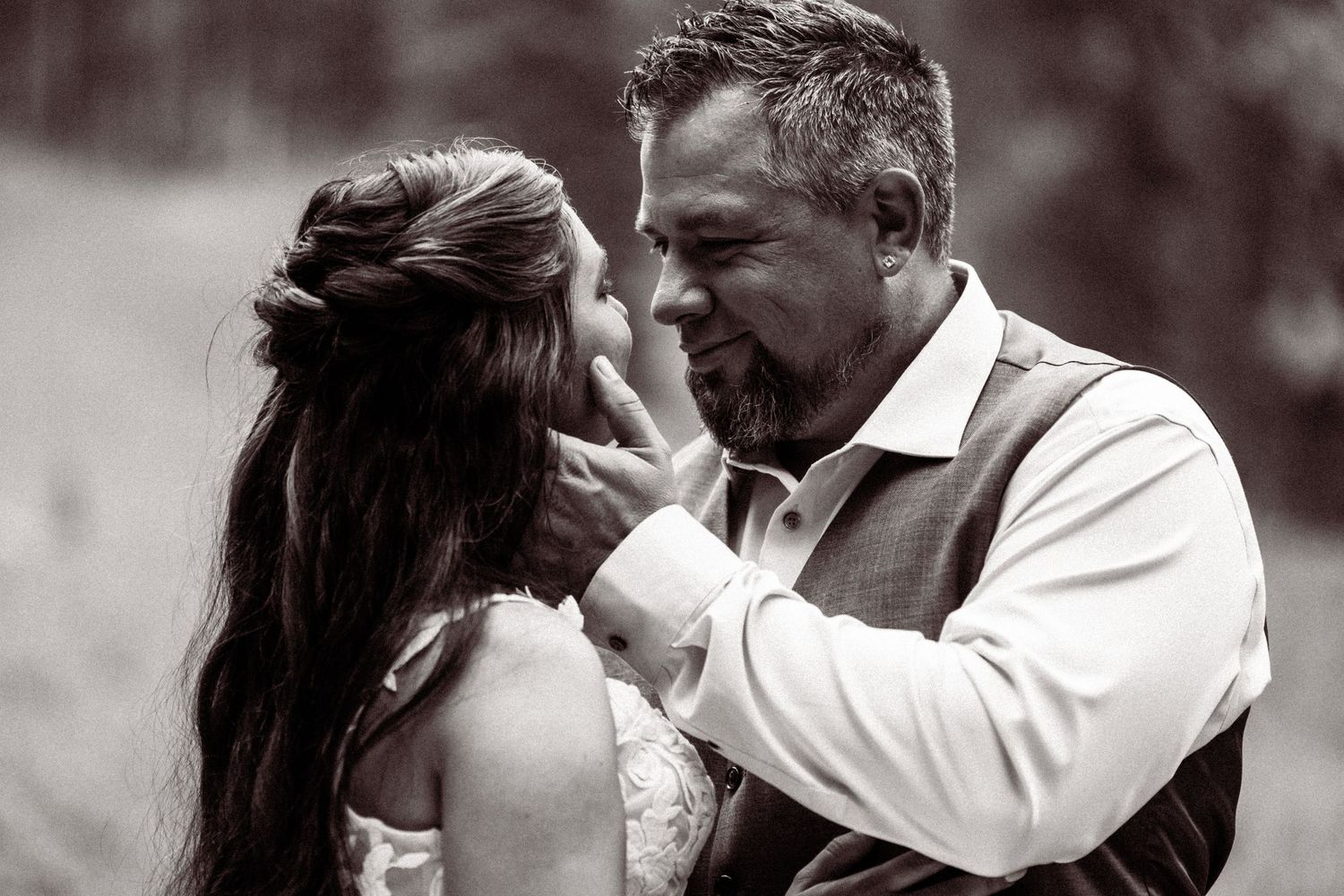 Black and white intimate portrait of groom tenderly holding brides face while gazing at each other.