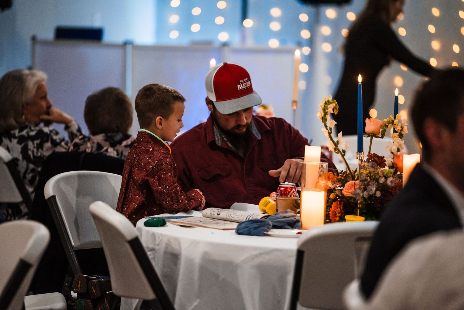 Wedding guests enjoy a festive holiday dinner with candlelight at decorated tables.