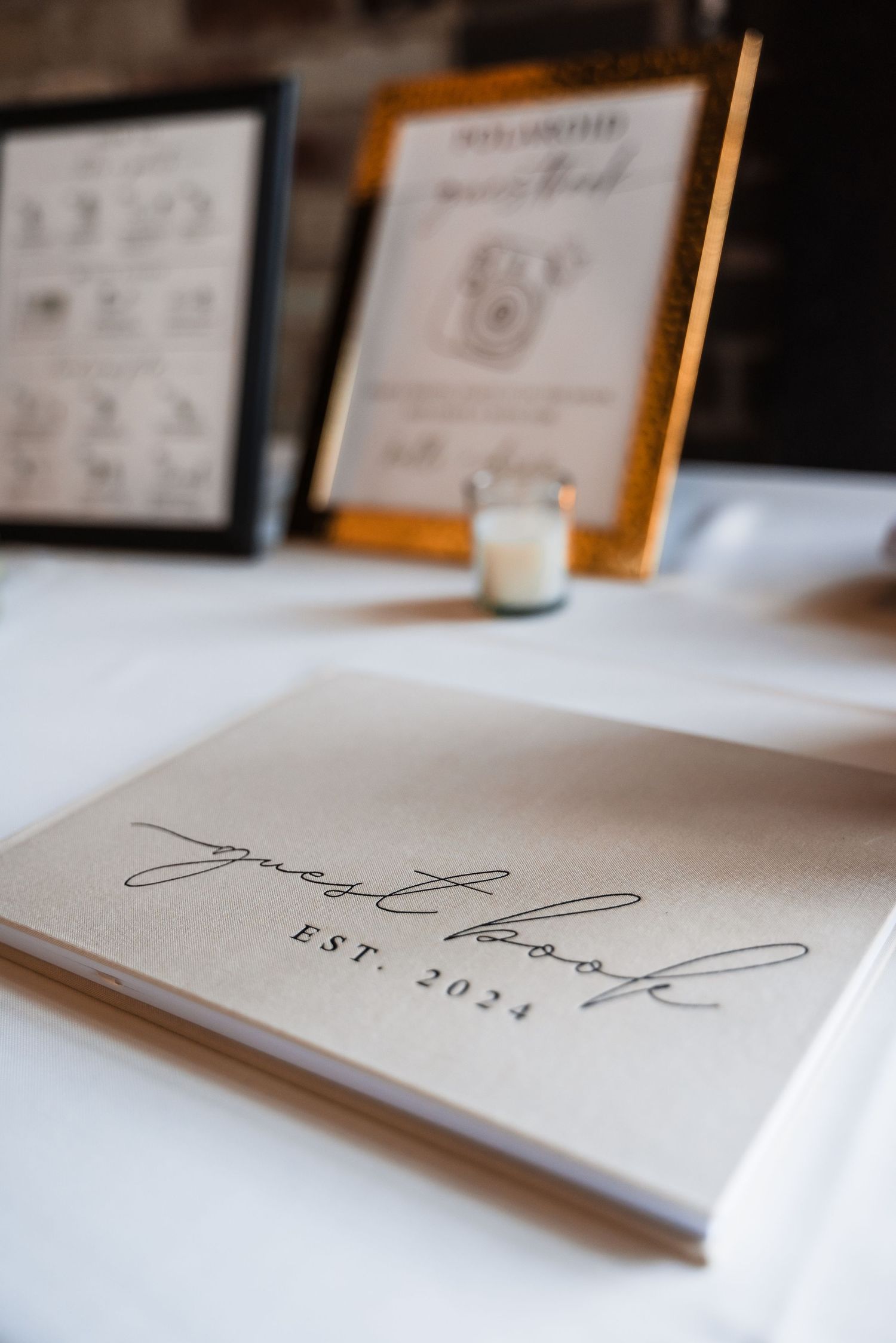 Elegant wedding guestbook or album with cursive text displayed on a white tablecloth.