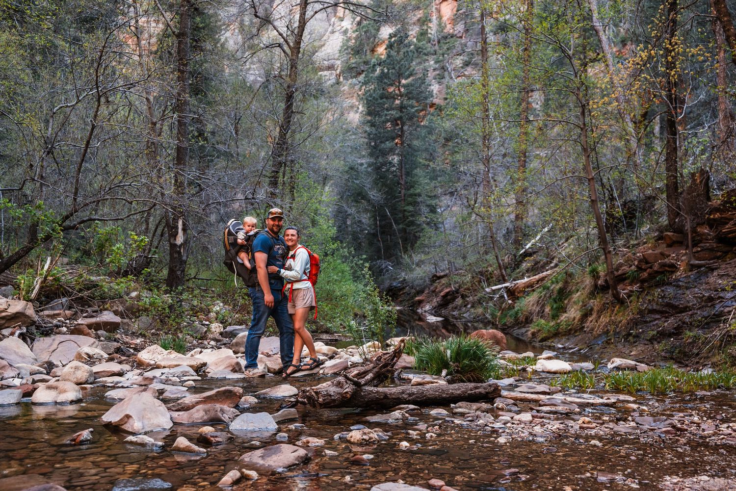 Couple enjoying a scenic hike along a rocky stream in a misty forest landscape.