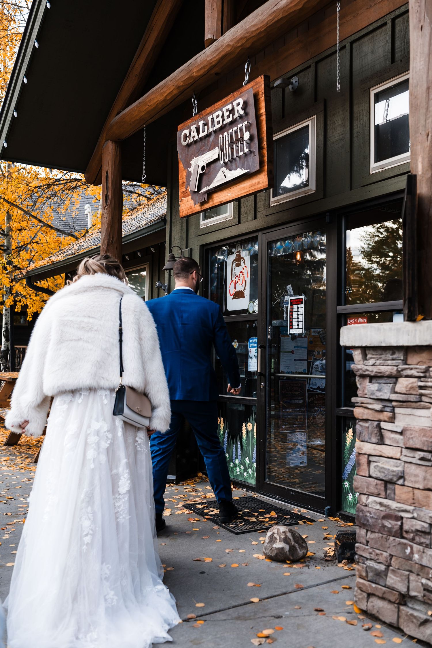 White wedding dress displayed against stone wall with autumn foliage overhead.