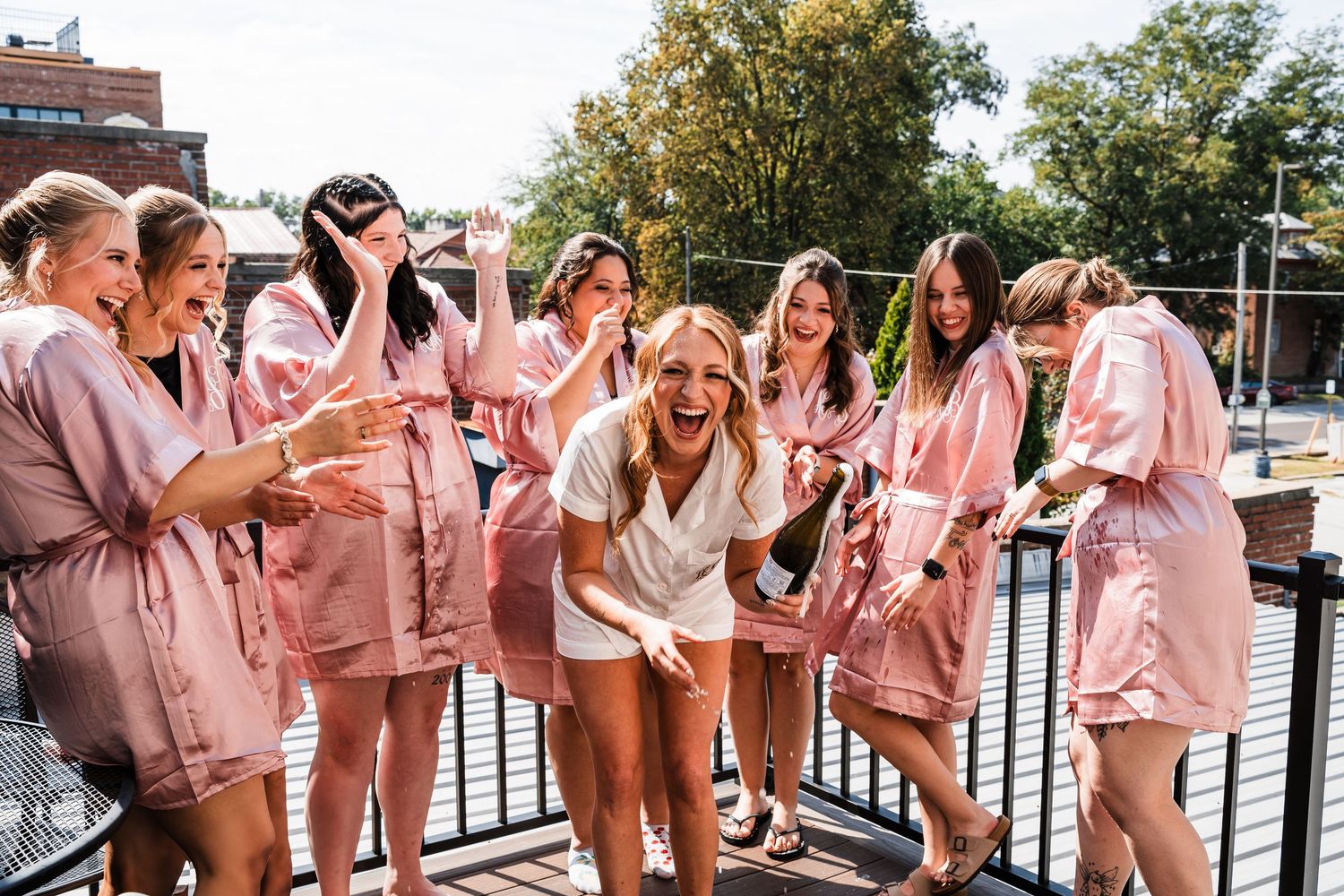 A group wearing matching pink robes celebrates joyfully together outdoors.