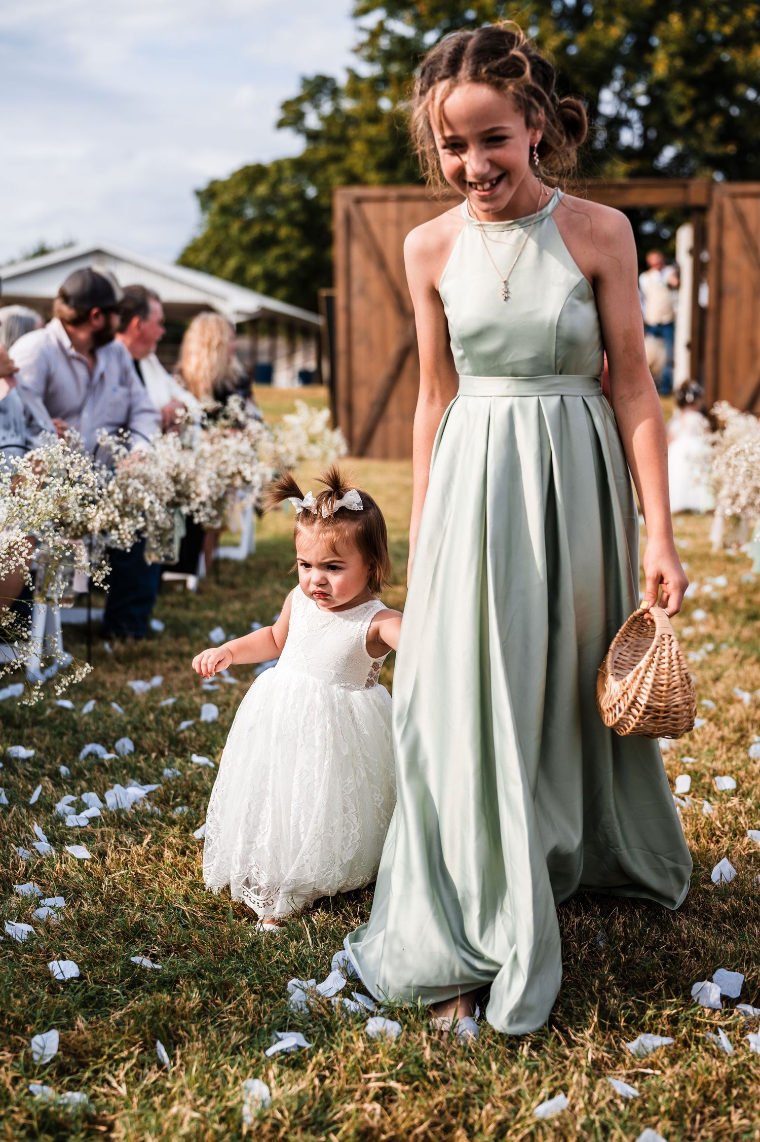 A sweet moment in a wildflower field with mint green and white dresses during an outdoor celebration.