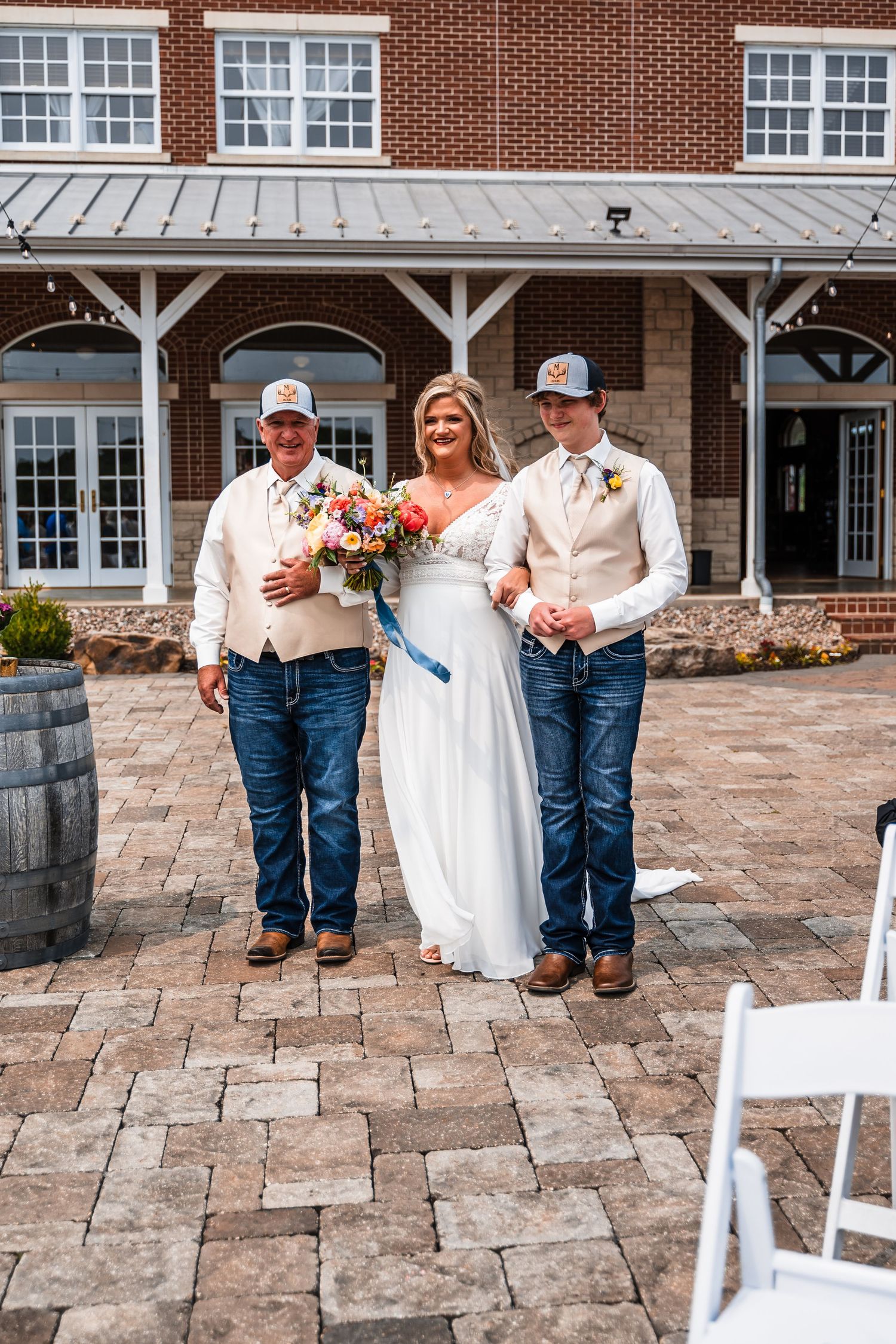 Wedding party poses together on stone patio in front of brick building with white columns.