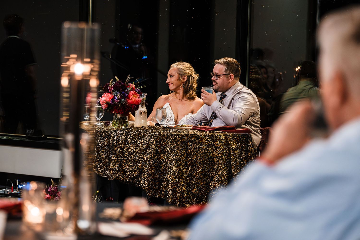 Wedding reception guests seated at long tables with candlelight and rustic decor.