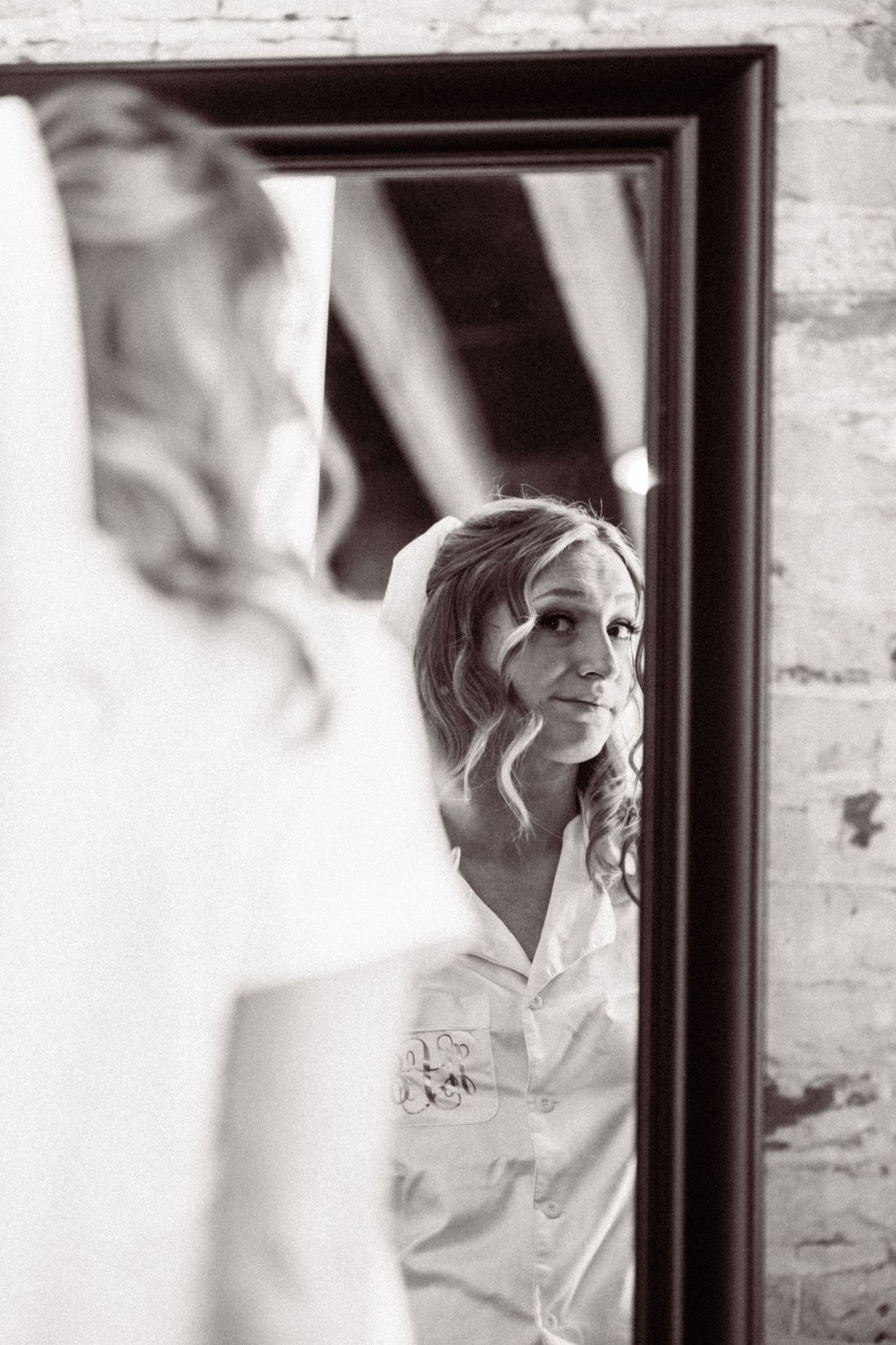 Black and white reflections in a mirror show a bride getting ready on her wedding morning.