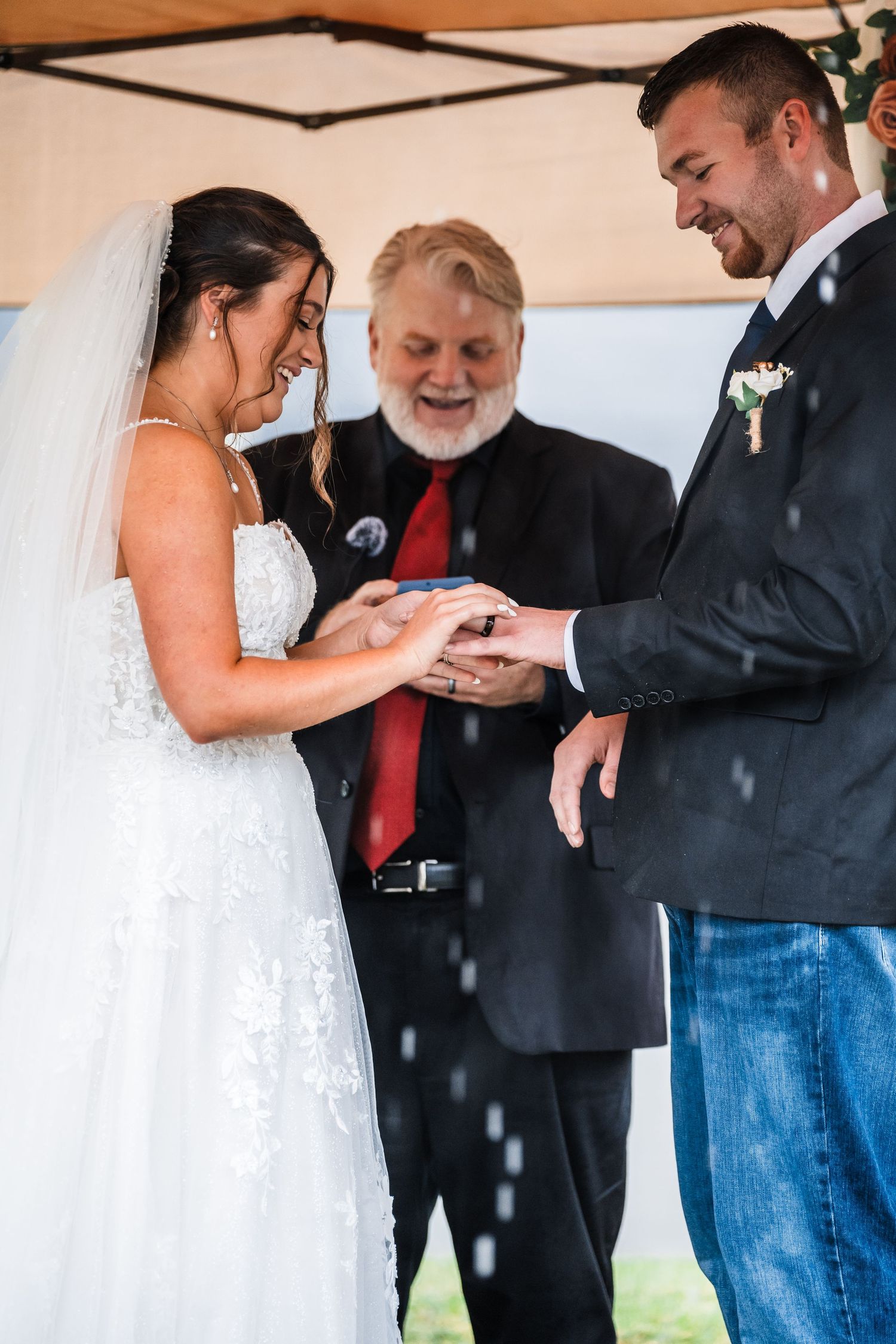Emotional wedding ceremony moments showing ring exchanges and laughter under a covered venue.