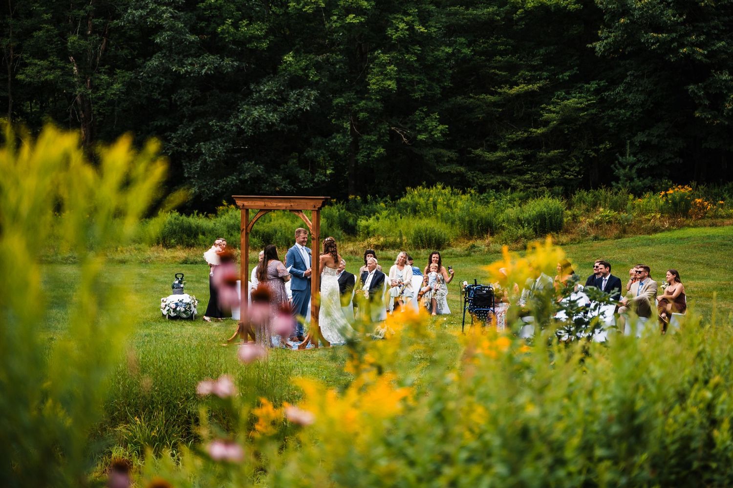 Garden wedding venue with yellow wildflowers and guests seated for an outdoor ceremony.