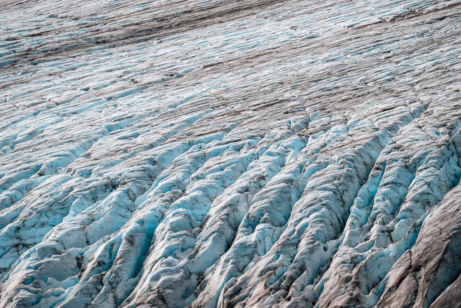 Close-up aerial view of a glacier's blue ice formations and crevasses showing intricate natural patterns and textures.