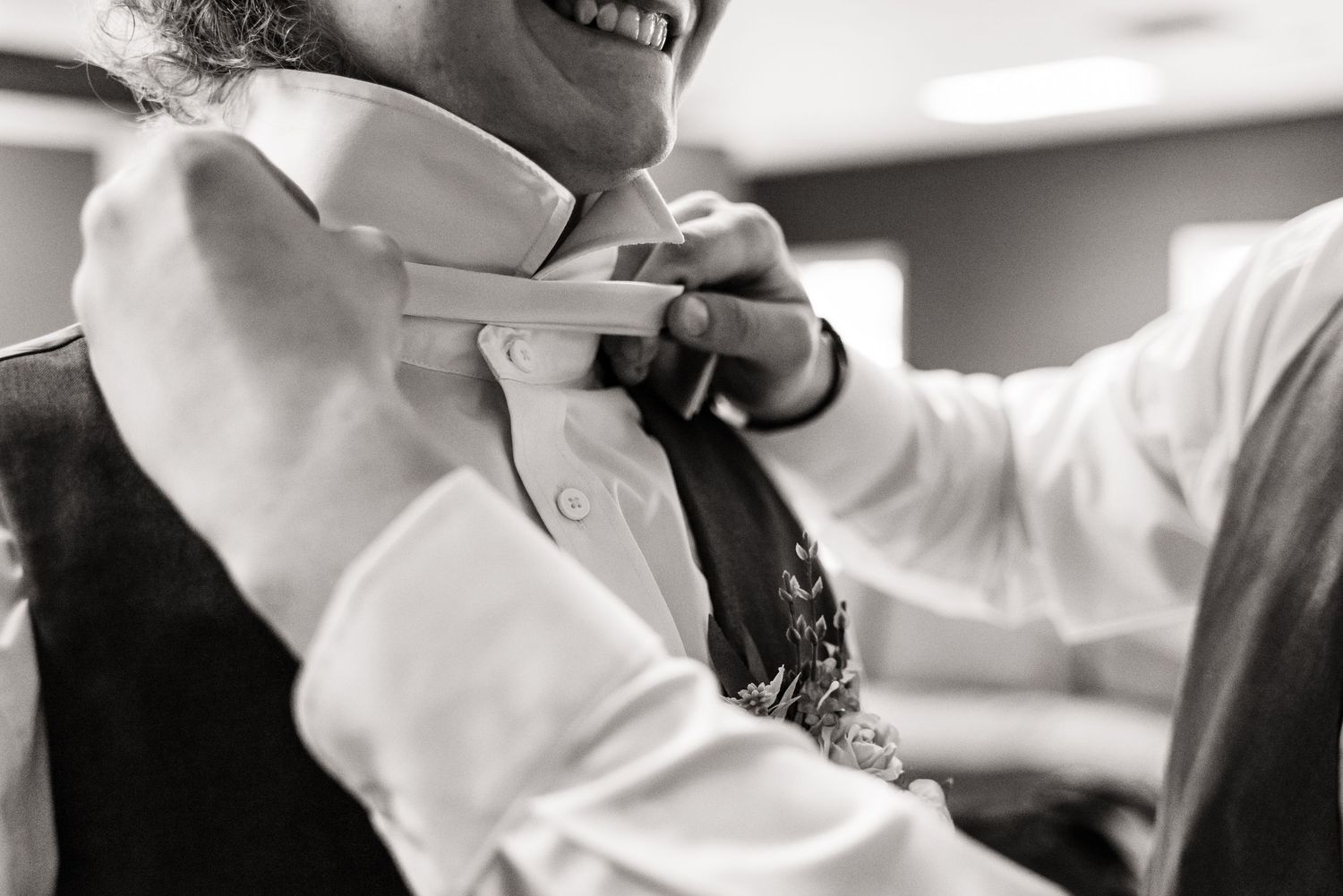 Close-up black and white shot of someone adjusting a bowtie before a formal event.