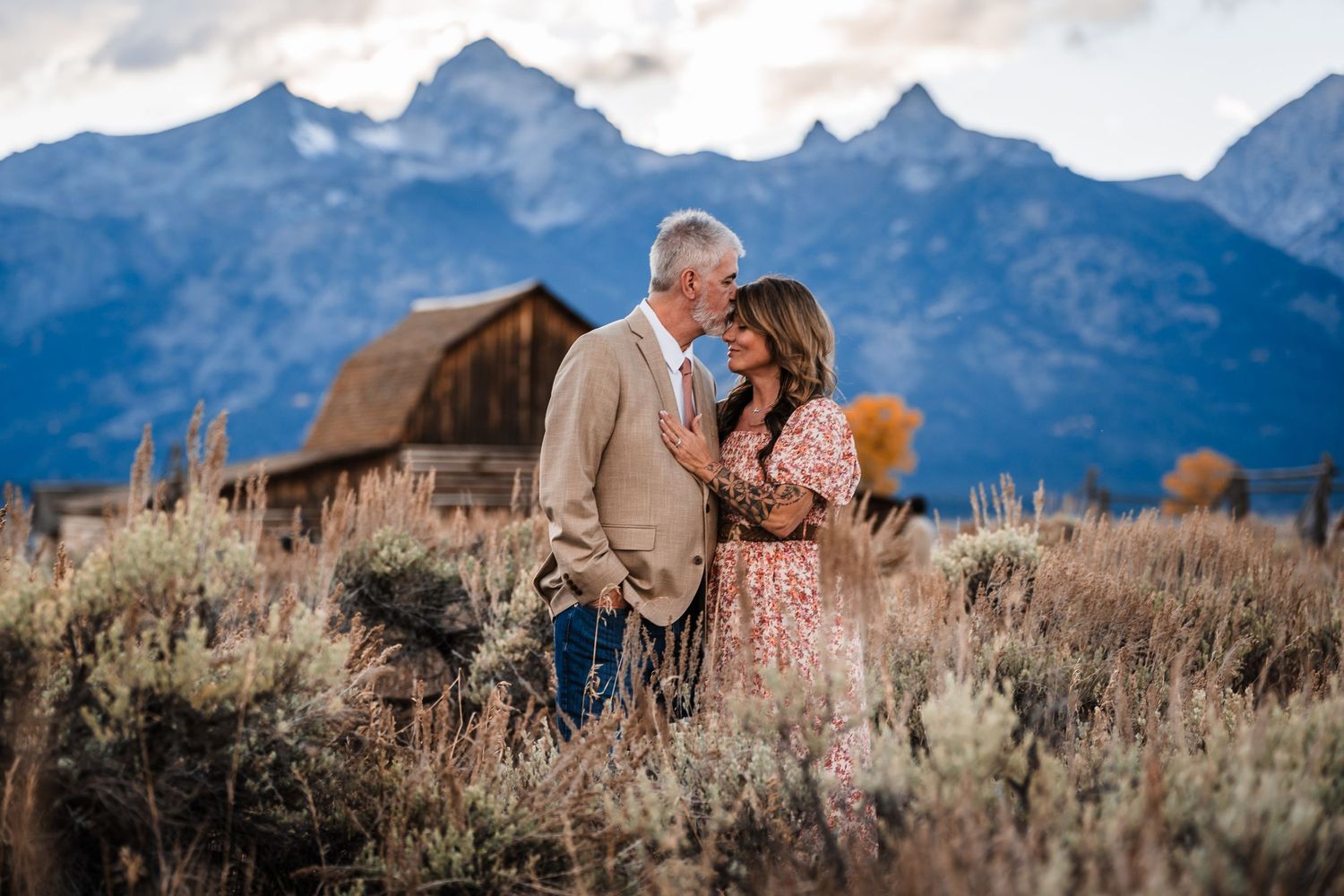 A couple shares a romantic moment in front of the majestic Grand Teton mountains during a sunset photo session.