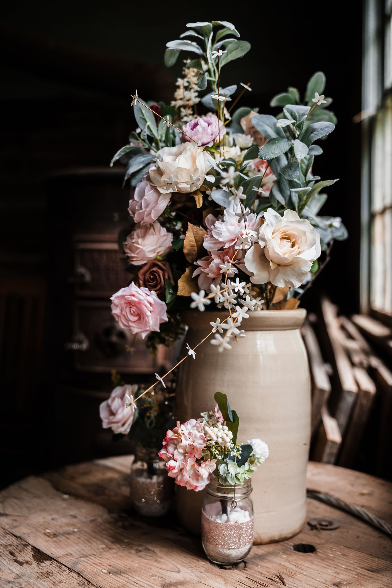 Delicate pink and white floral arrangements in vintage vases create a romantic wedding centerpiece.
