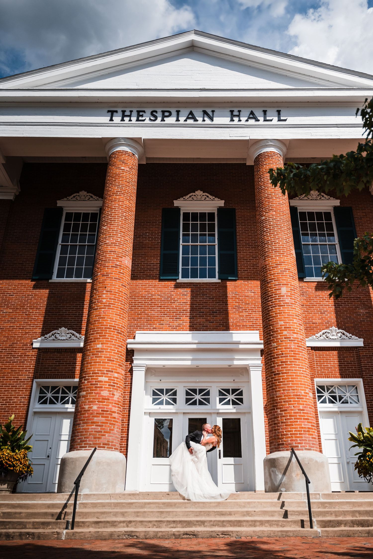 Wedding photos taken in front of Thespian Hall, a classic brick building with white columns.