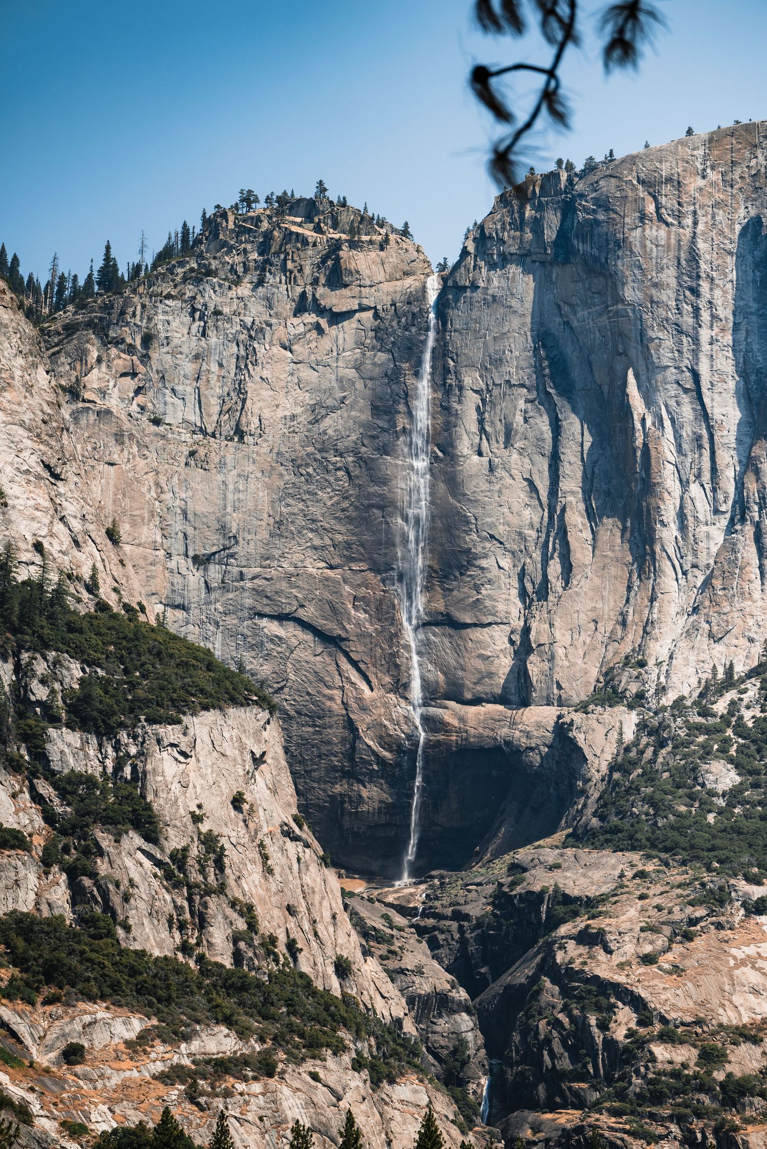 Dramatic granite cliffs of Yosemite Valley with waterfalls cascading down steep rock faces.