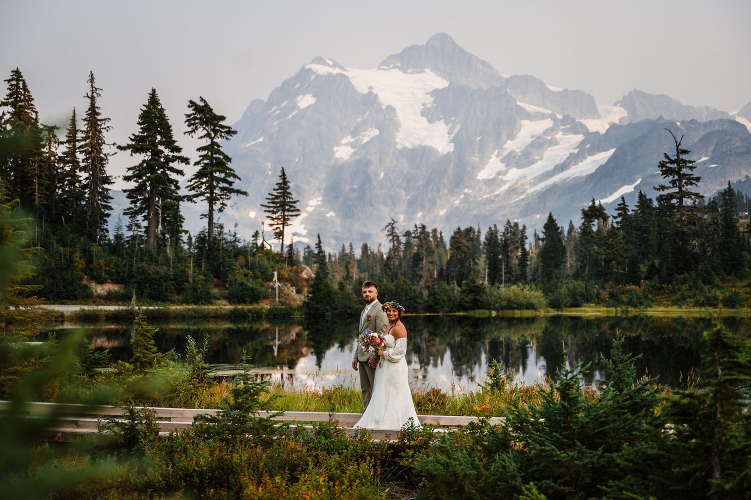 A scenic mountain lake reflects snow-capped peaks as a couple celebrates their wedding day.