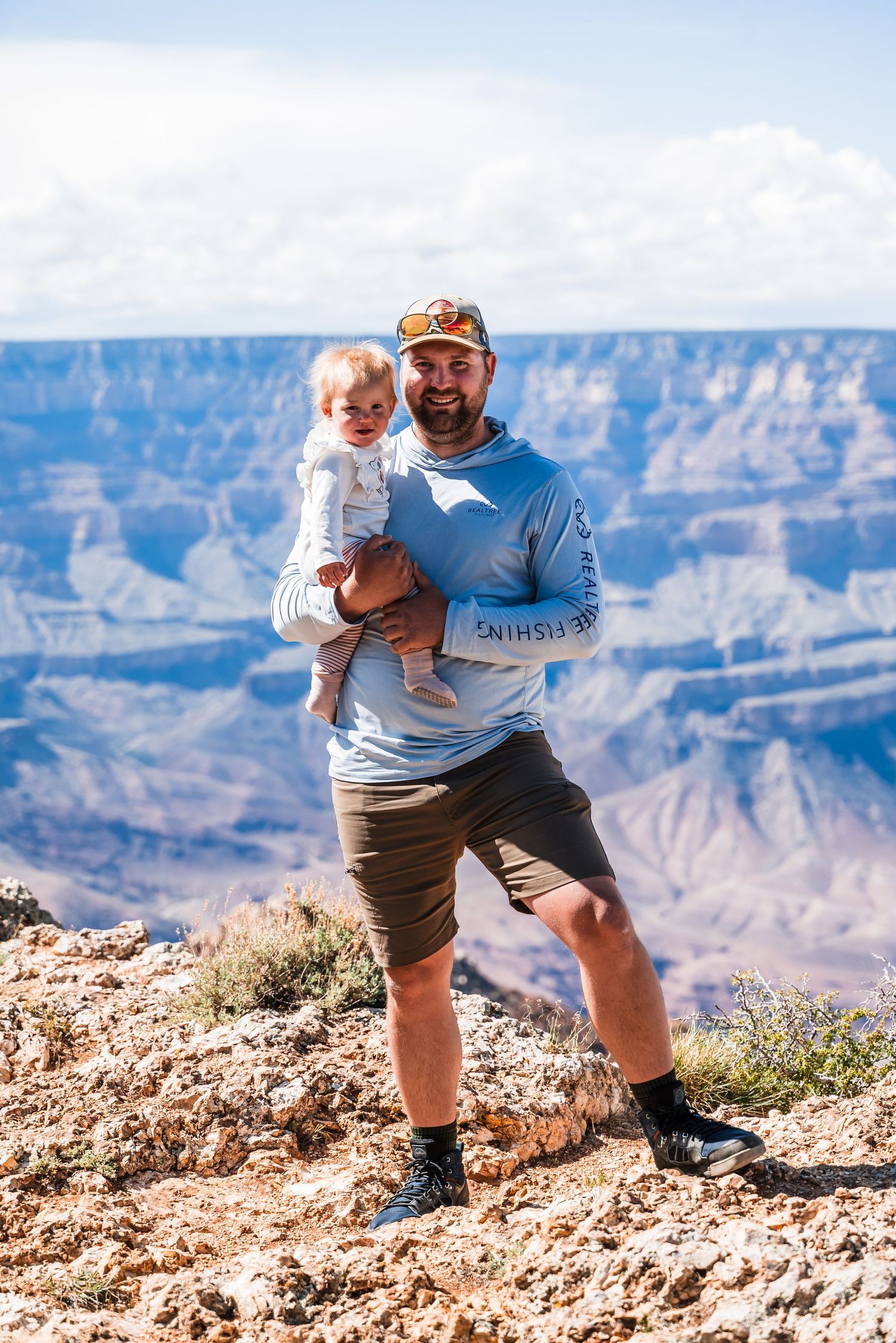 Tourists taking in the breathtaking views at a Grand Canyon viewpoint on a sunny afternoon.
