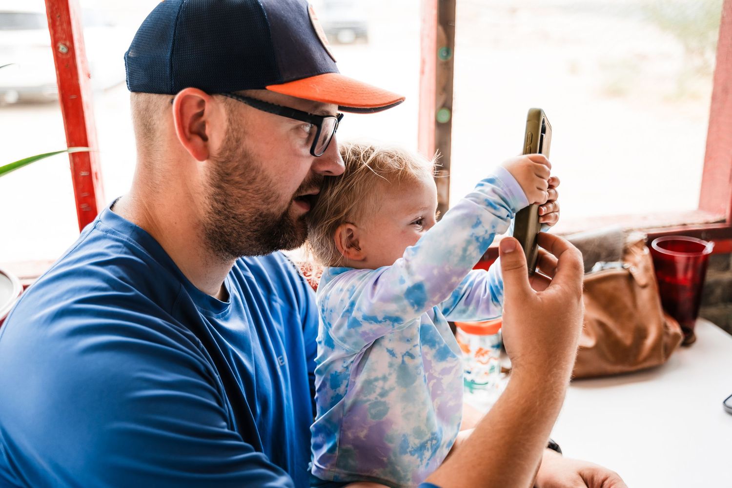A parent and child looking at something on a mobile device while sitting indoors.